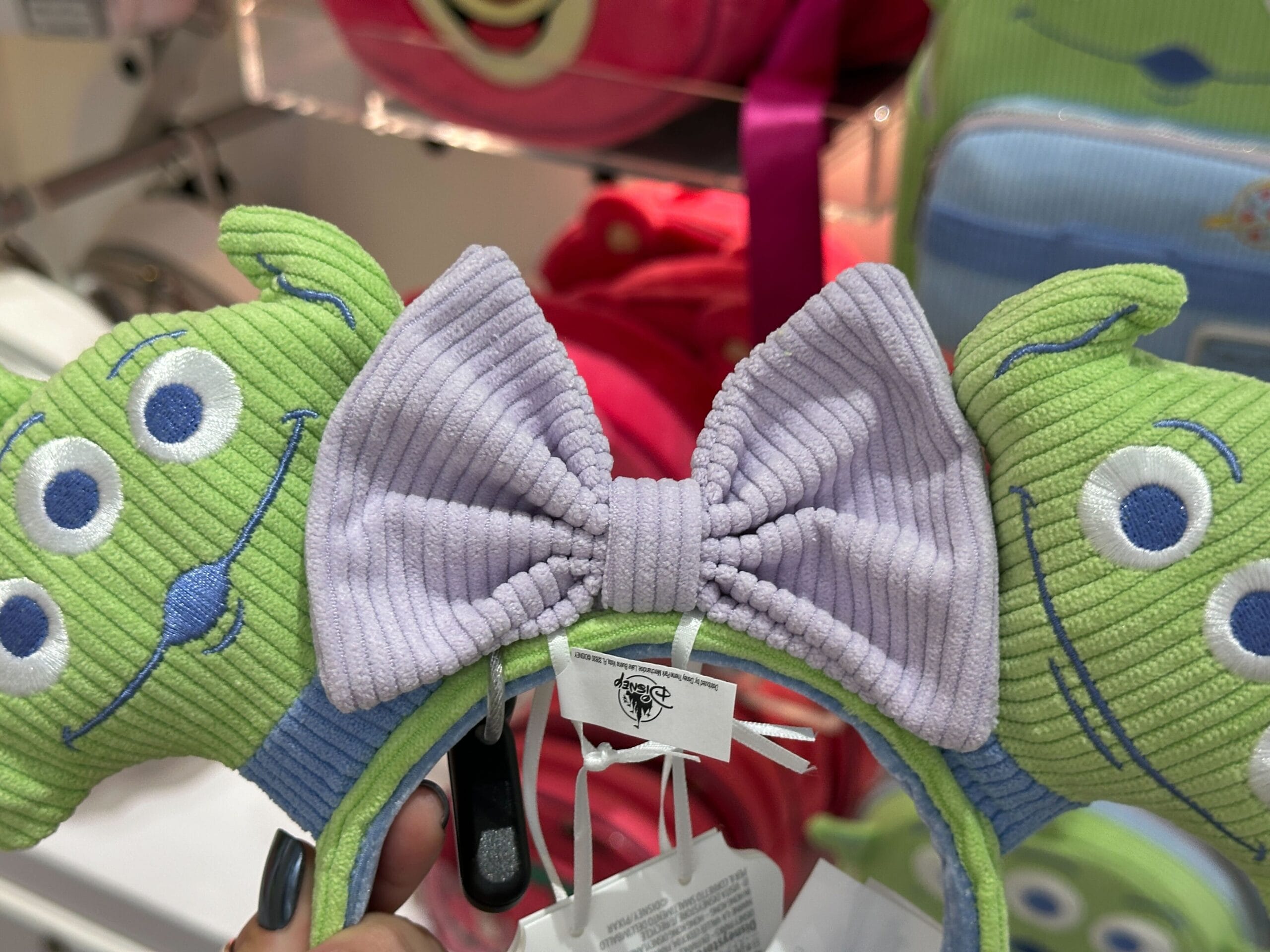 A headband with two Toy Story Alien faces and a ribbed lavender bow, perfect for any Loungefly Collection display.