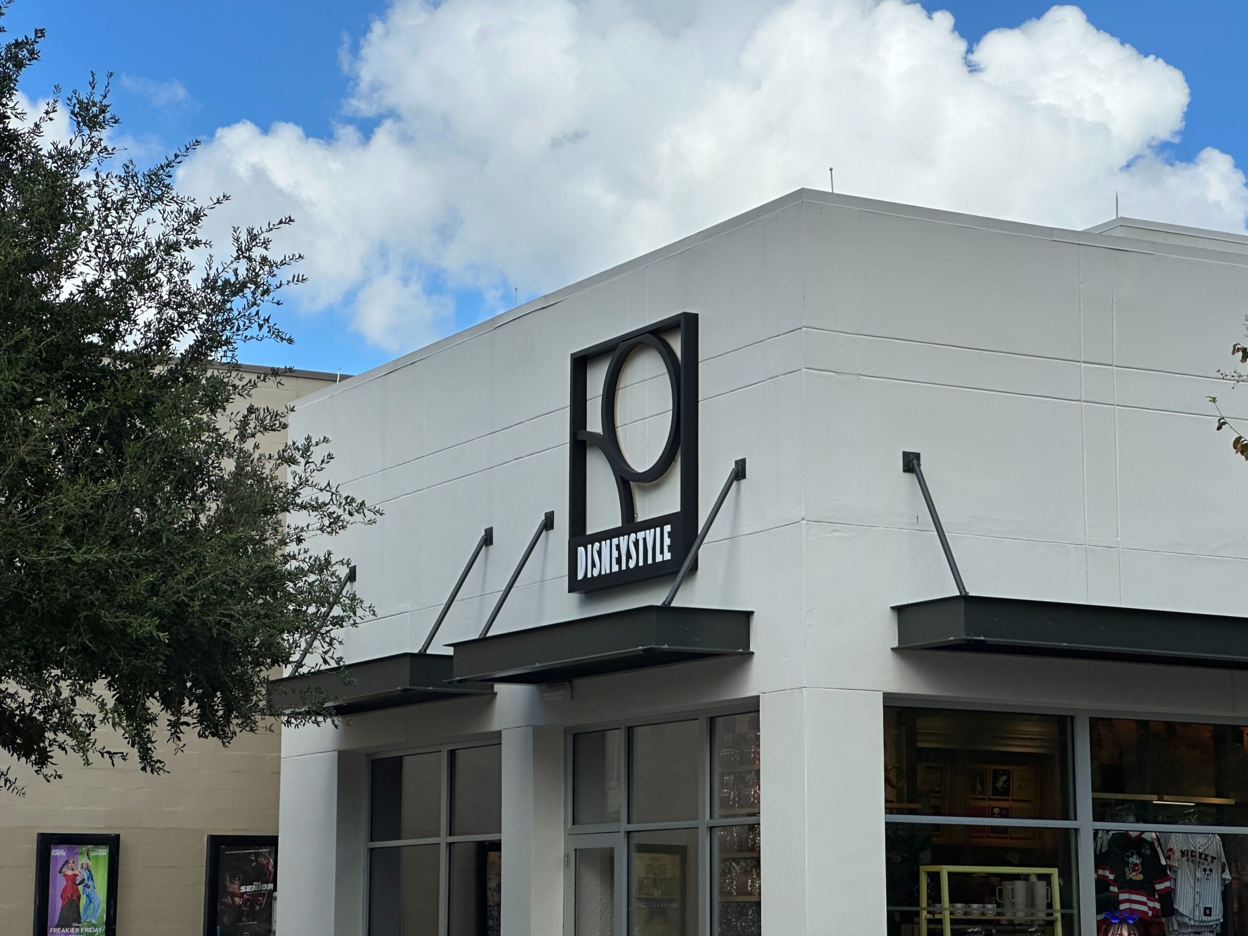 A white building with a "DISNEYSTYLE" sign, a large abstract logo, and Disney World vibes above the entrance.