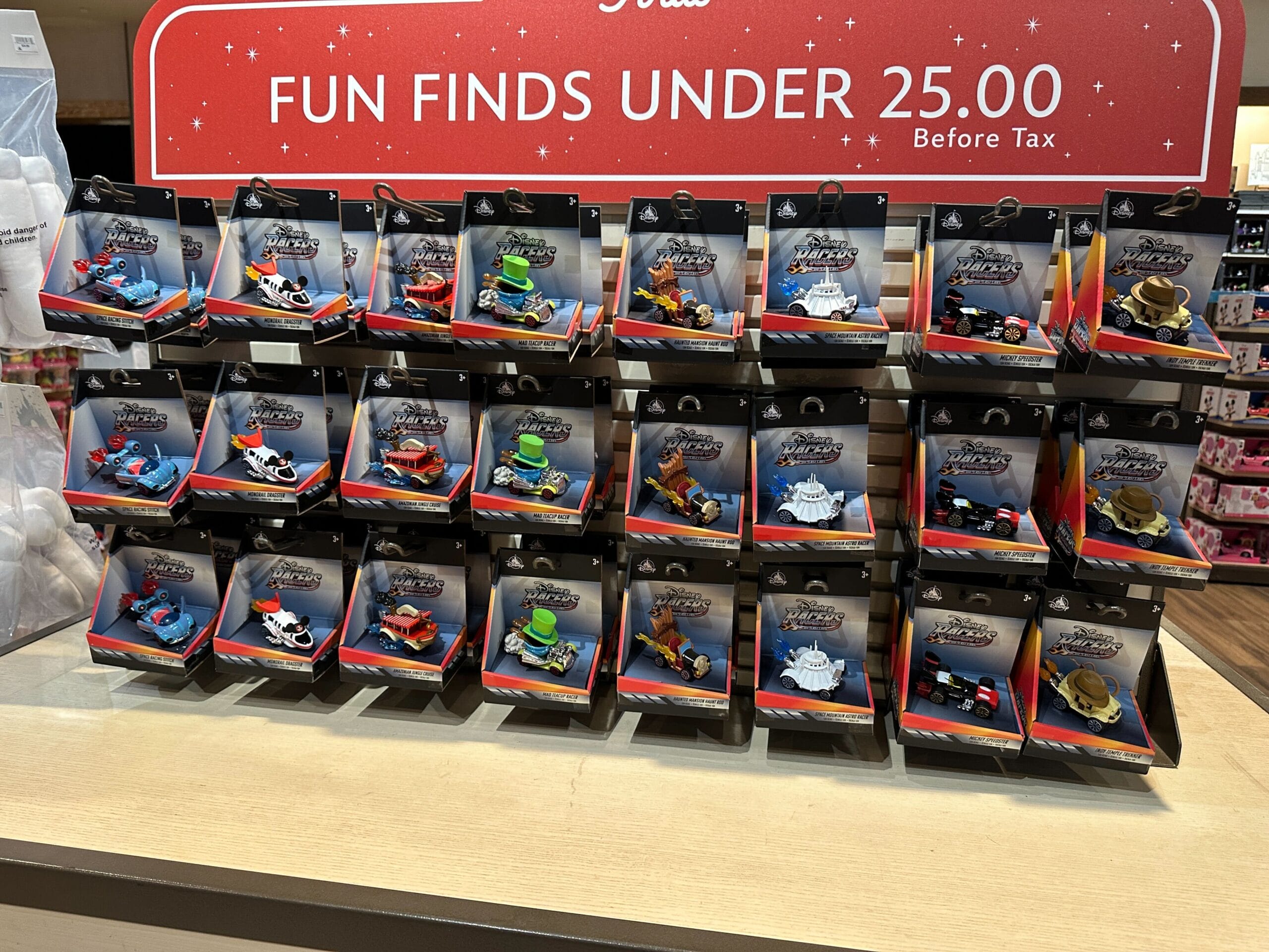 Disney Racers Toy cars displayed on shelves under a red “FUN FINDS UNDER 25.00 Before Tax” sign.