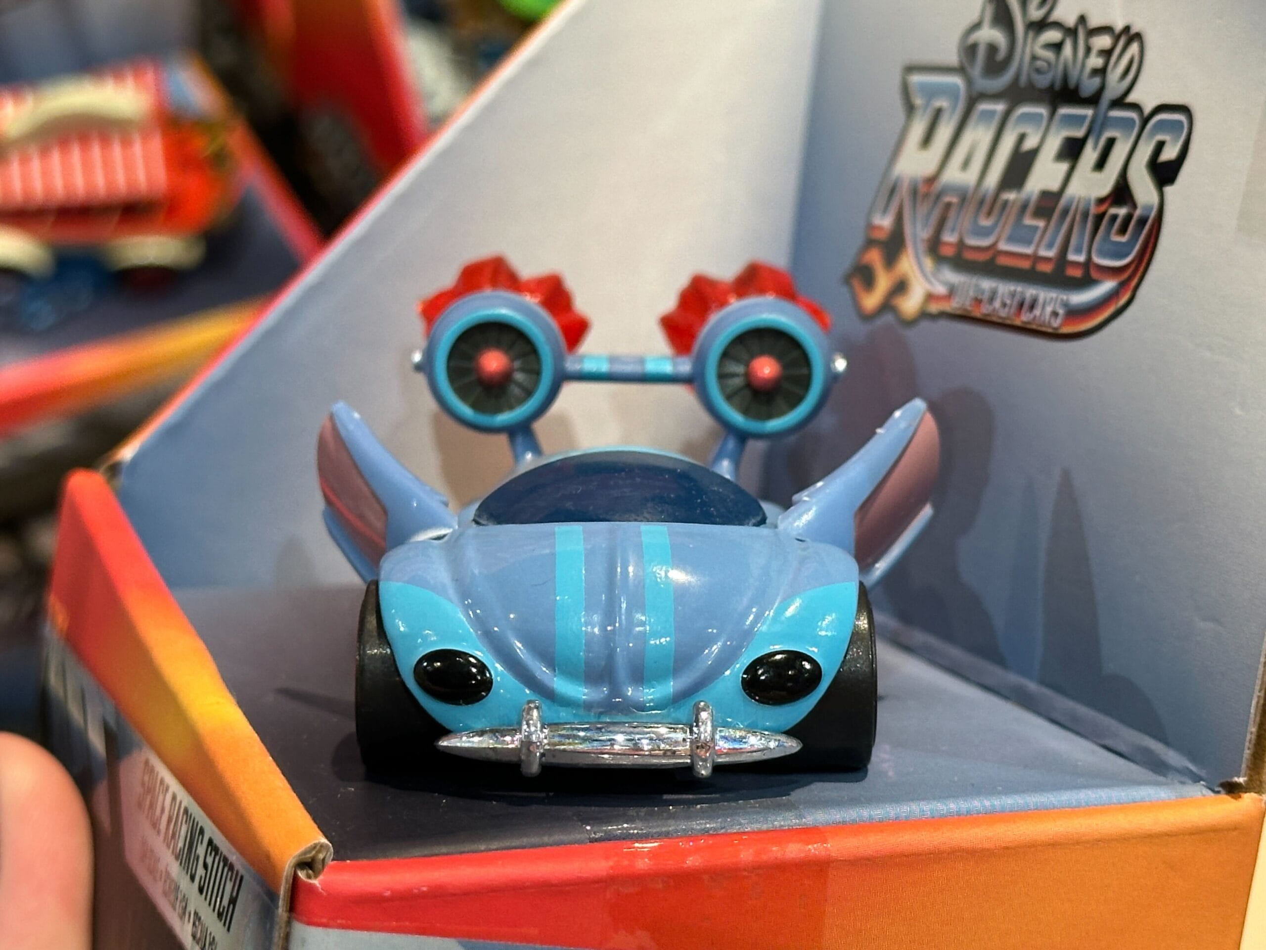 A blue Disney Racers Toy car with red turbines and raised doors, displayed in themed Disney Racers packaging.