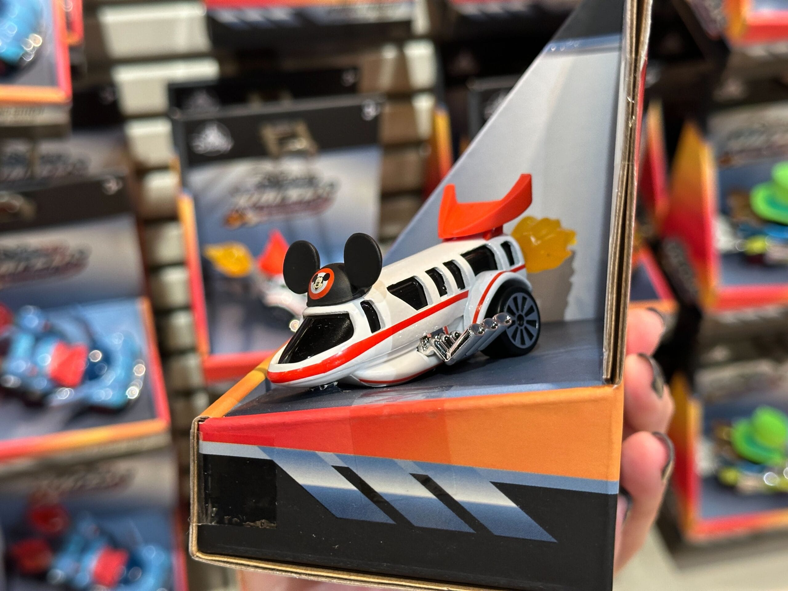 A Disney World Monorail car with Mickey Mouse ears is displayed in its packaging at a store.