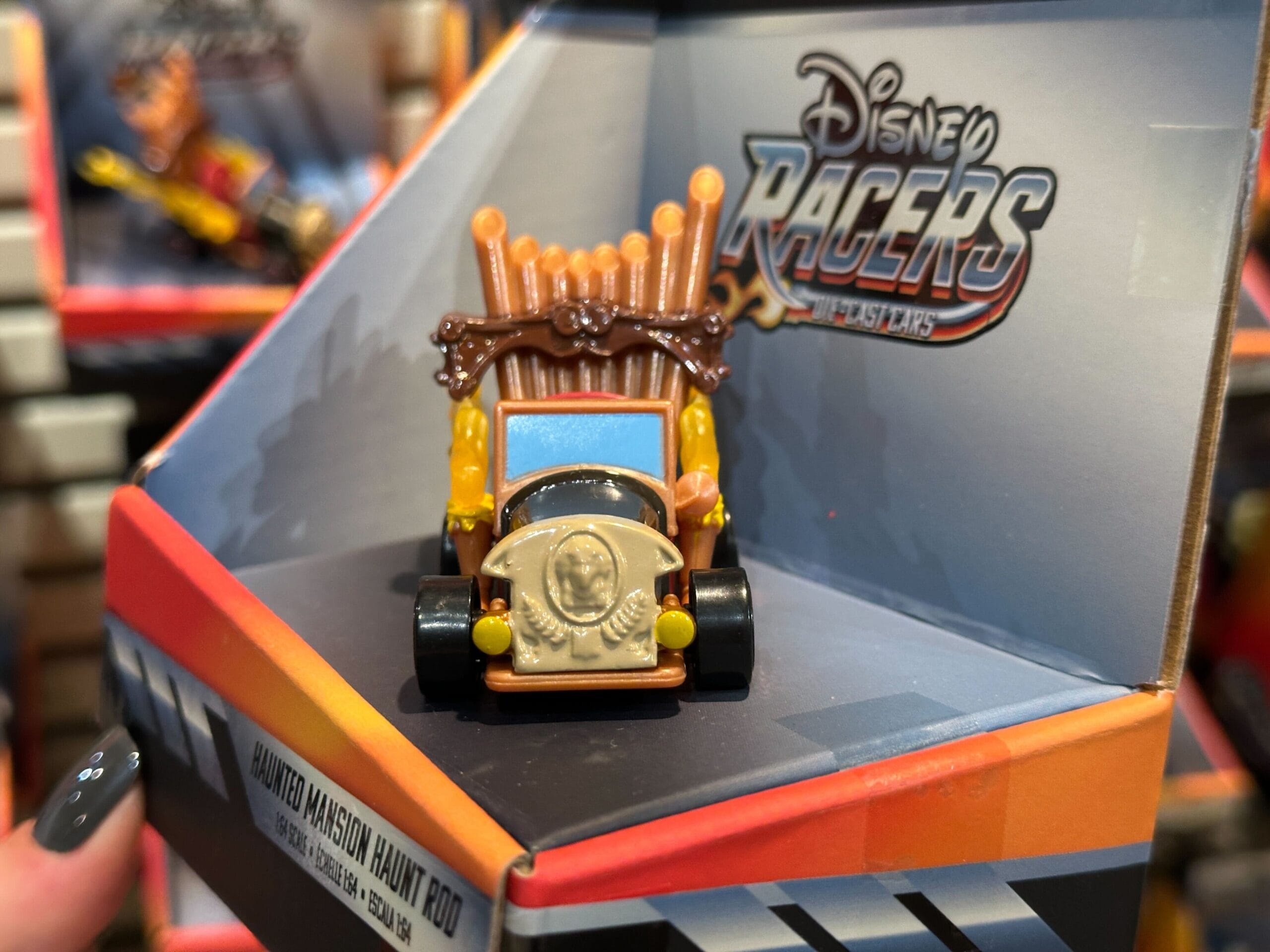 A Disney Racers toy car themed after the Haunted Mansion, displayed in its packaging at Disney World.
