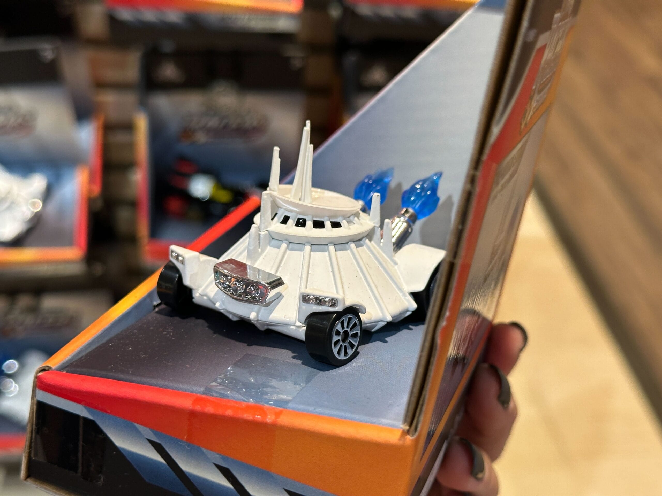 Close-up of a white Disney Racers toy car resembling a Star Wars Imperial Star Destroyer, displayed on a store shelf.