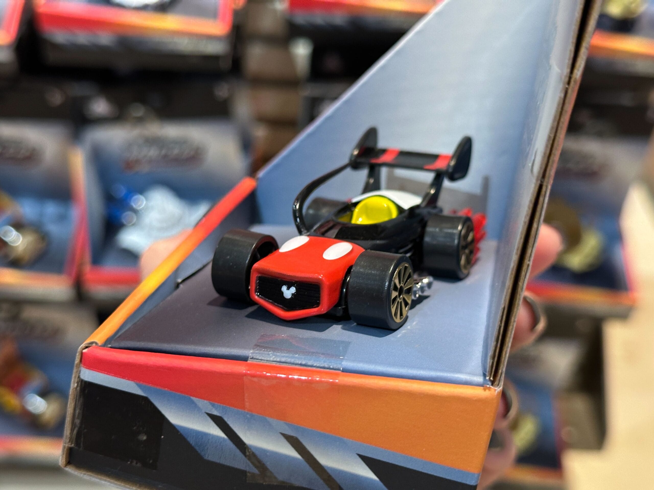 A close-up of a Disney Racers toy race car in black and red on a display shelf in a store.