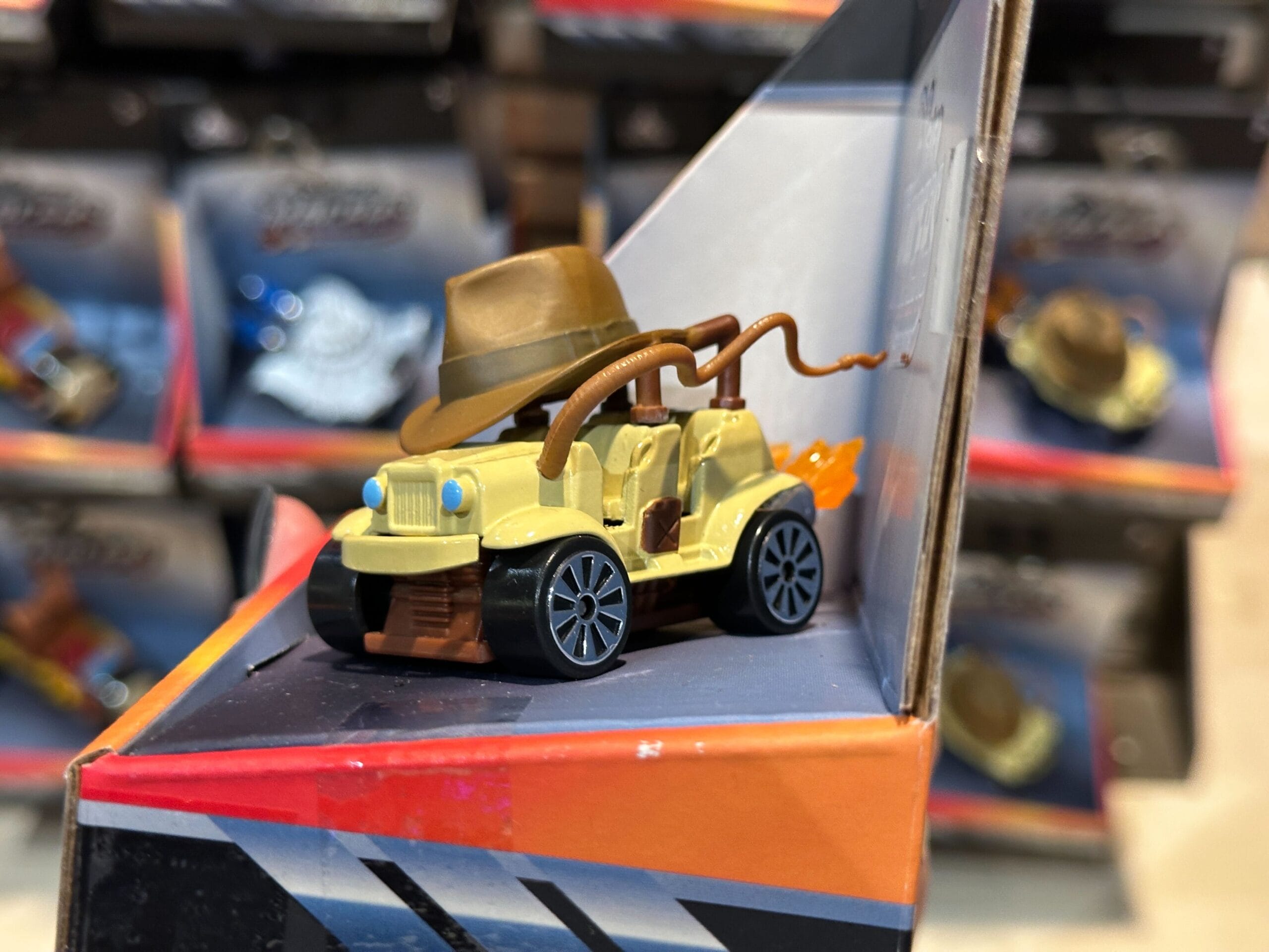 A Disney Racers Toy car with a brown hat and whip, inspired by Jungle Cruise, displayed on a store shelf.