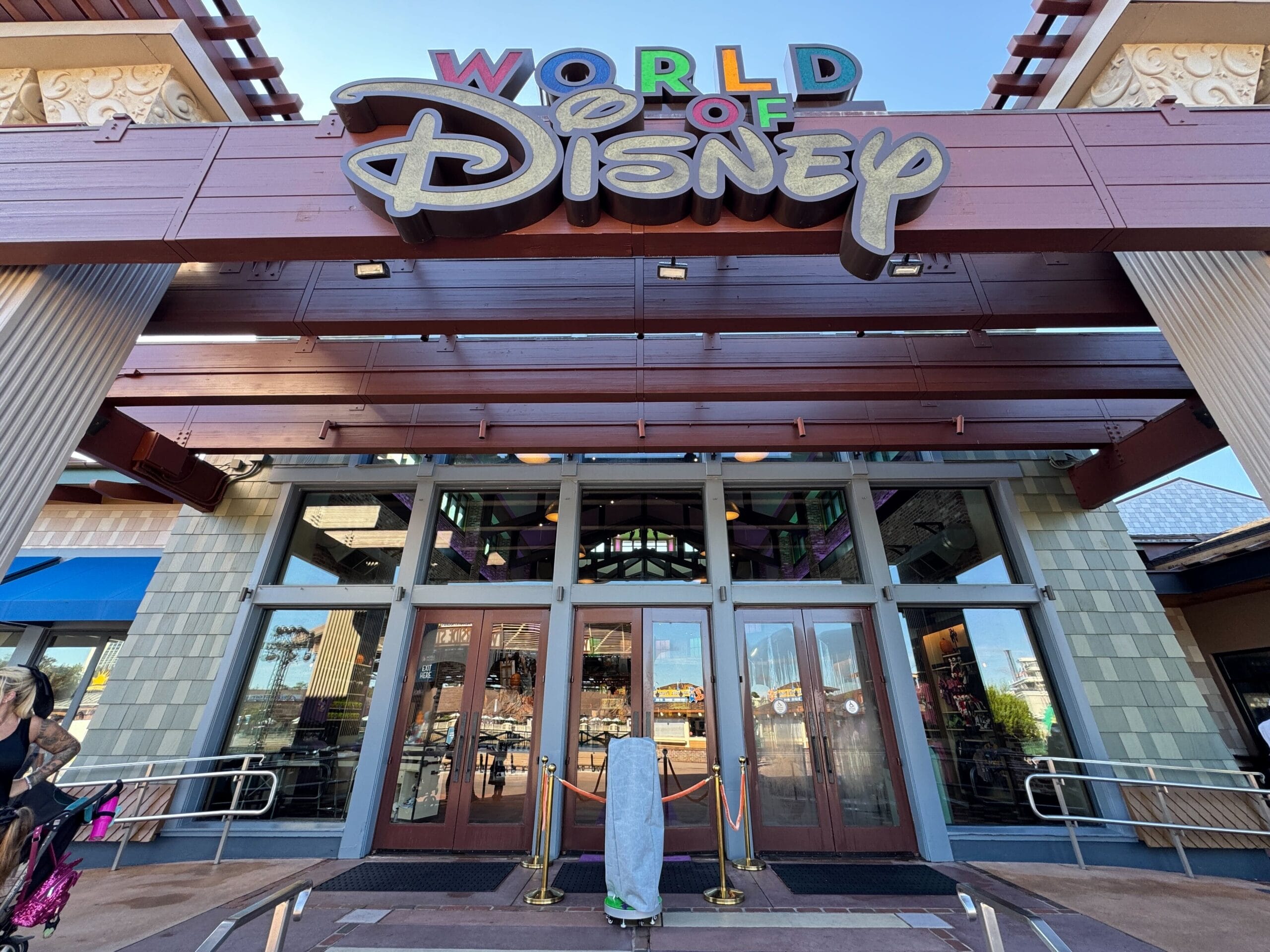 Entrance of the World of Disney store at Disney Springs with vibrant sign above glass doors on a sunny day.