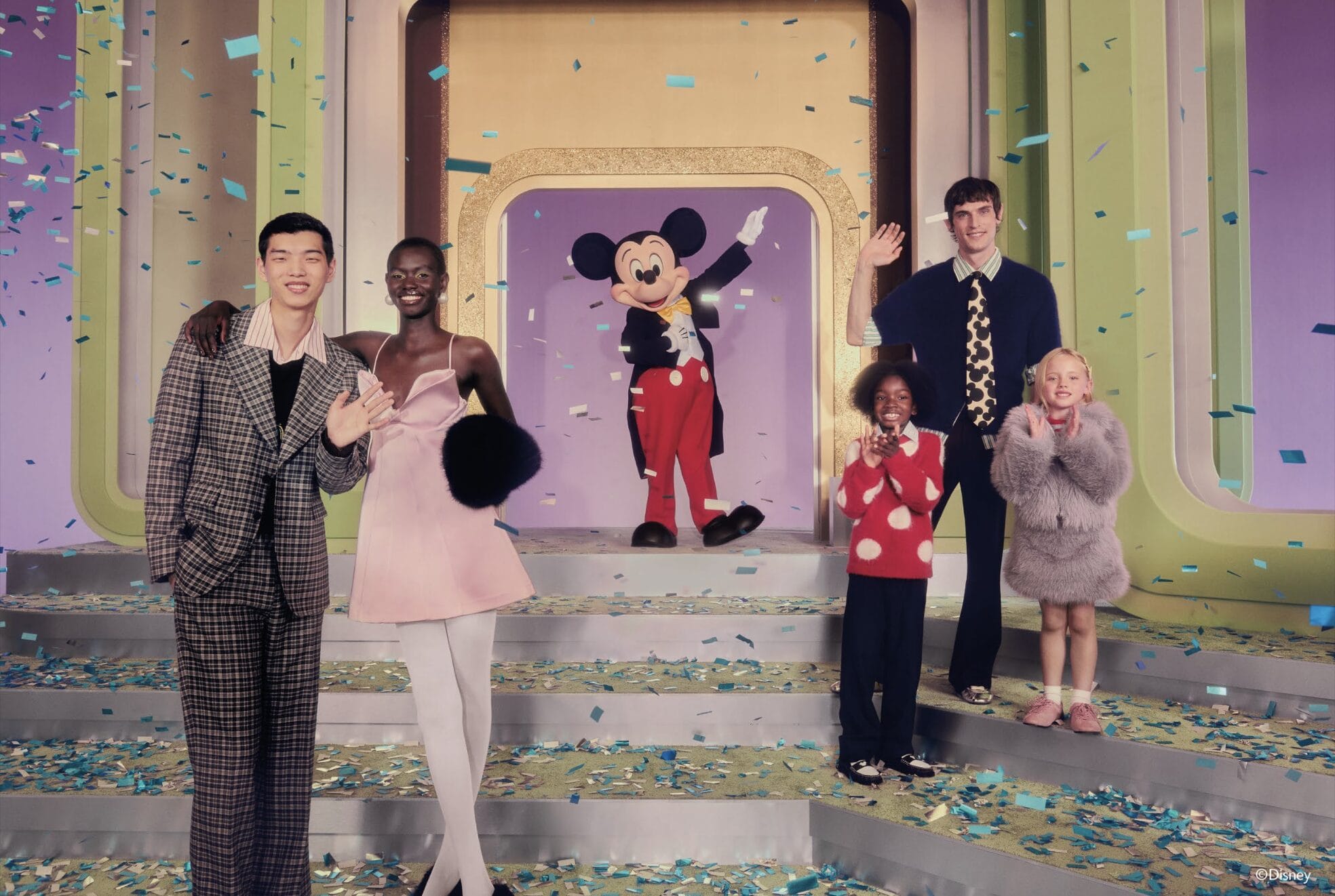Five people and Mickey Mouse wave amid confetti on a colorful Zara stage from the Disney Collection.