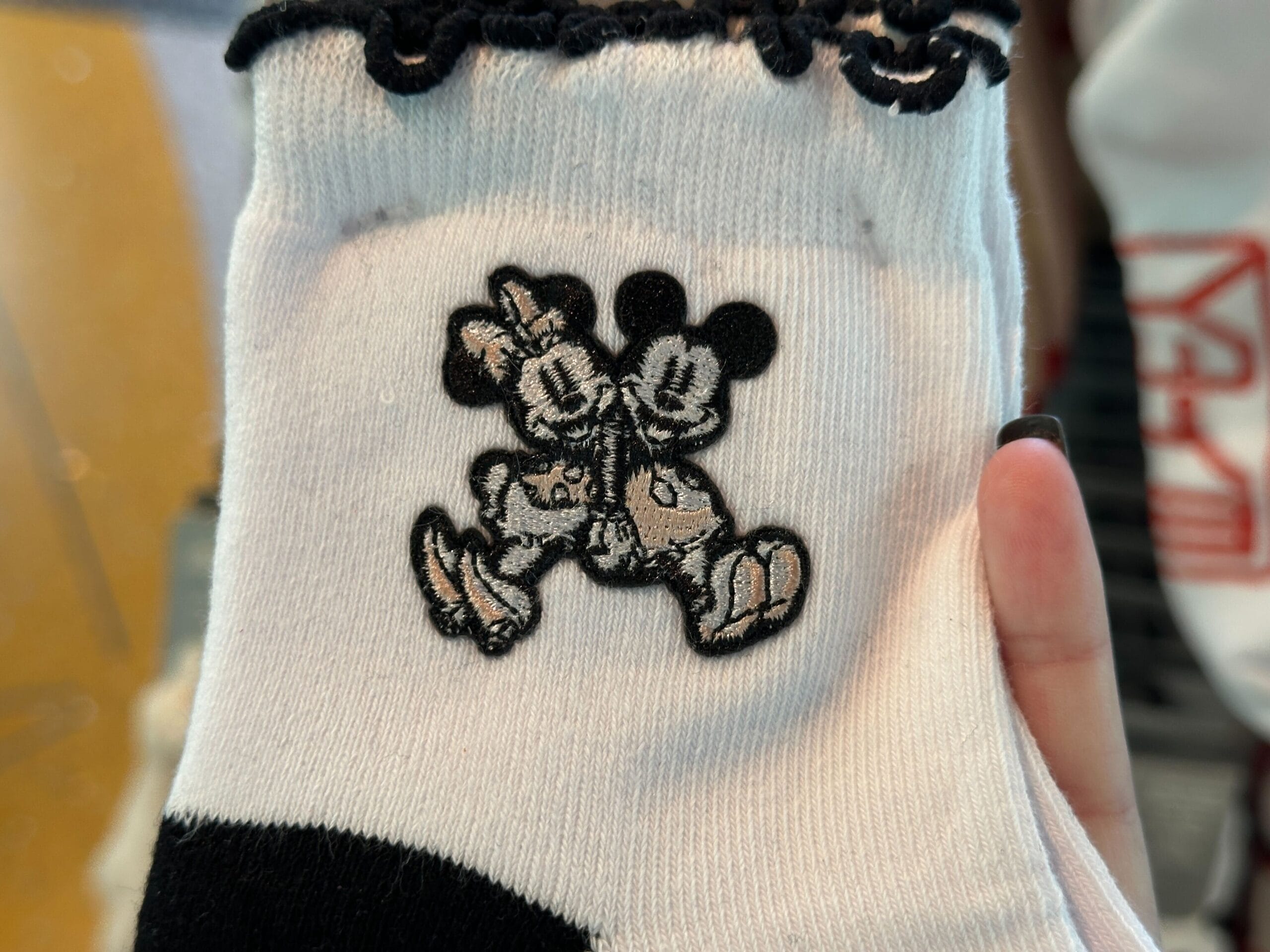 White Disney World novelty socks with black trim, featuring Mickey and Minnie Mouse sitting and holding hands.