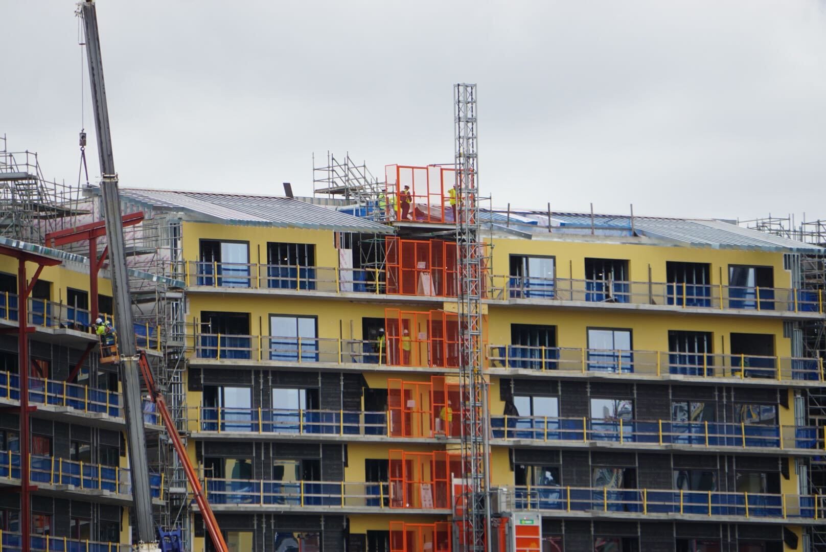 Construction workers and a crane work on the yellow and blue Lakeshore building in this latest Lakeshore Update.