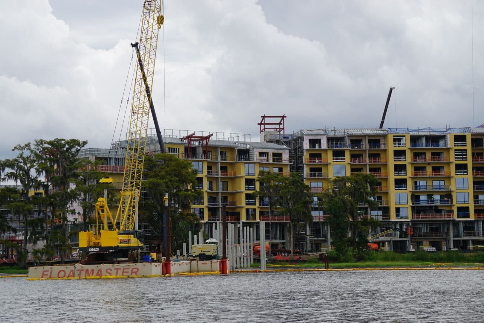 A yellow crane on a barge works riverside near a building under construction in this Lakeshore Update.