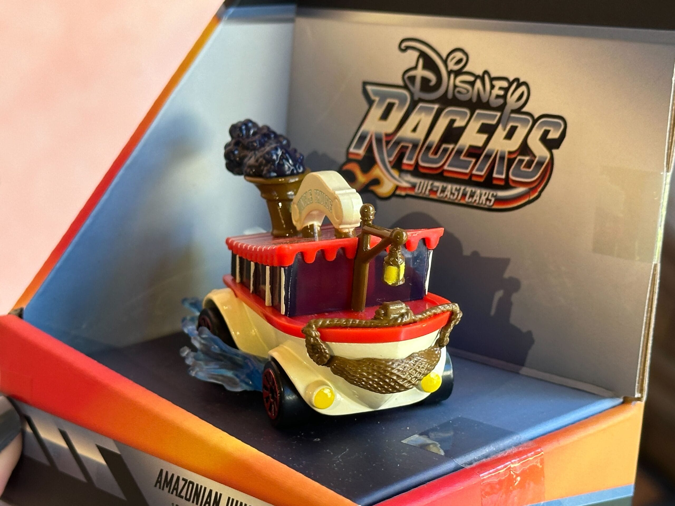 A toy riverboat car in red and white Disney Racers packaging, inspired by Jungle Cruise and labeled “Amazonian Jungle.”