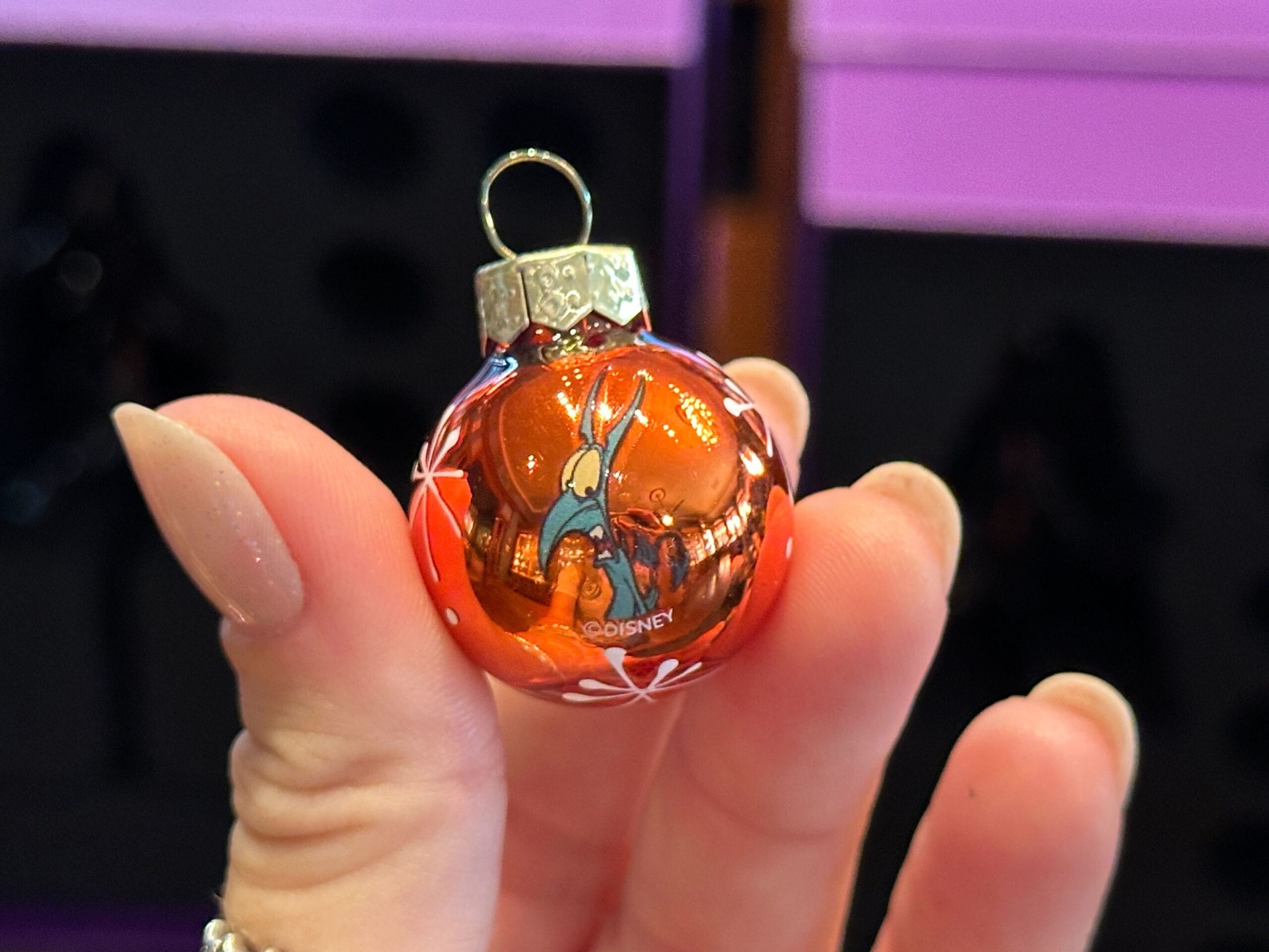 A hand holds a small red Disney World ornament featuring Thumper the rabbit from "Bambi.
