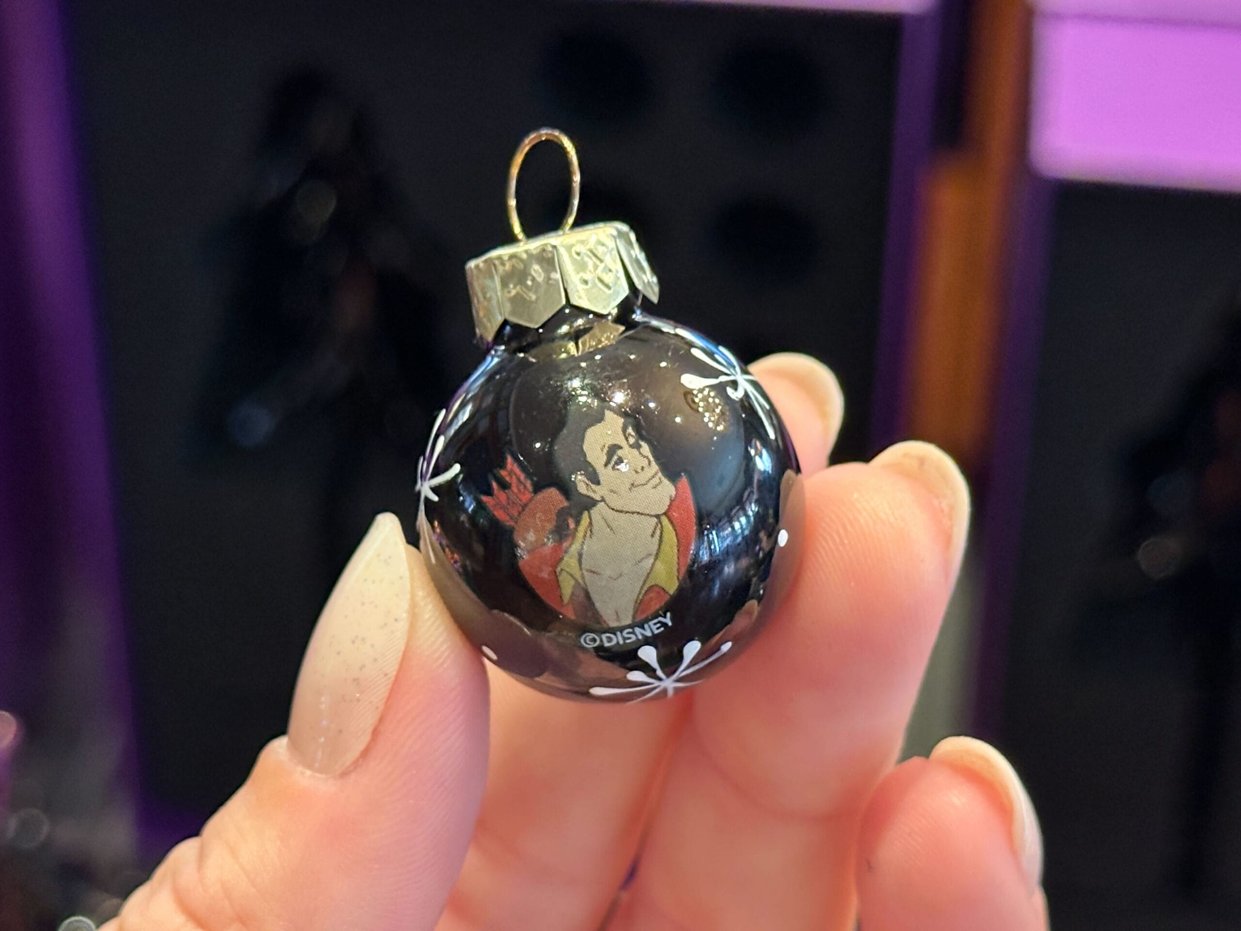 A hand holds a black Disney Villain Ornament featuring Gaston from "Beauty and the Beast.