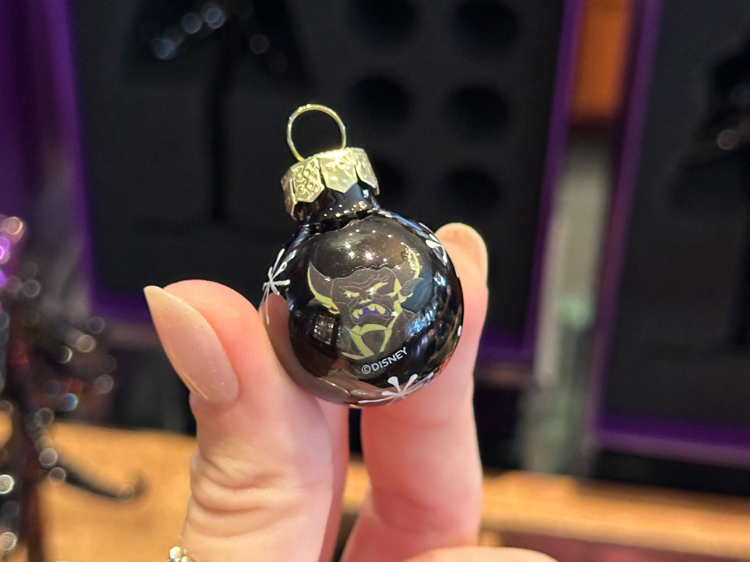 A hand holds a small black Villain Ornament featuring Disney’s Maleficent.