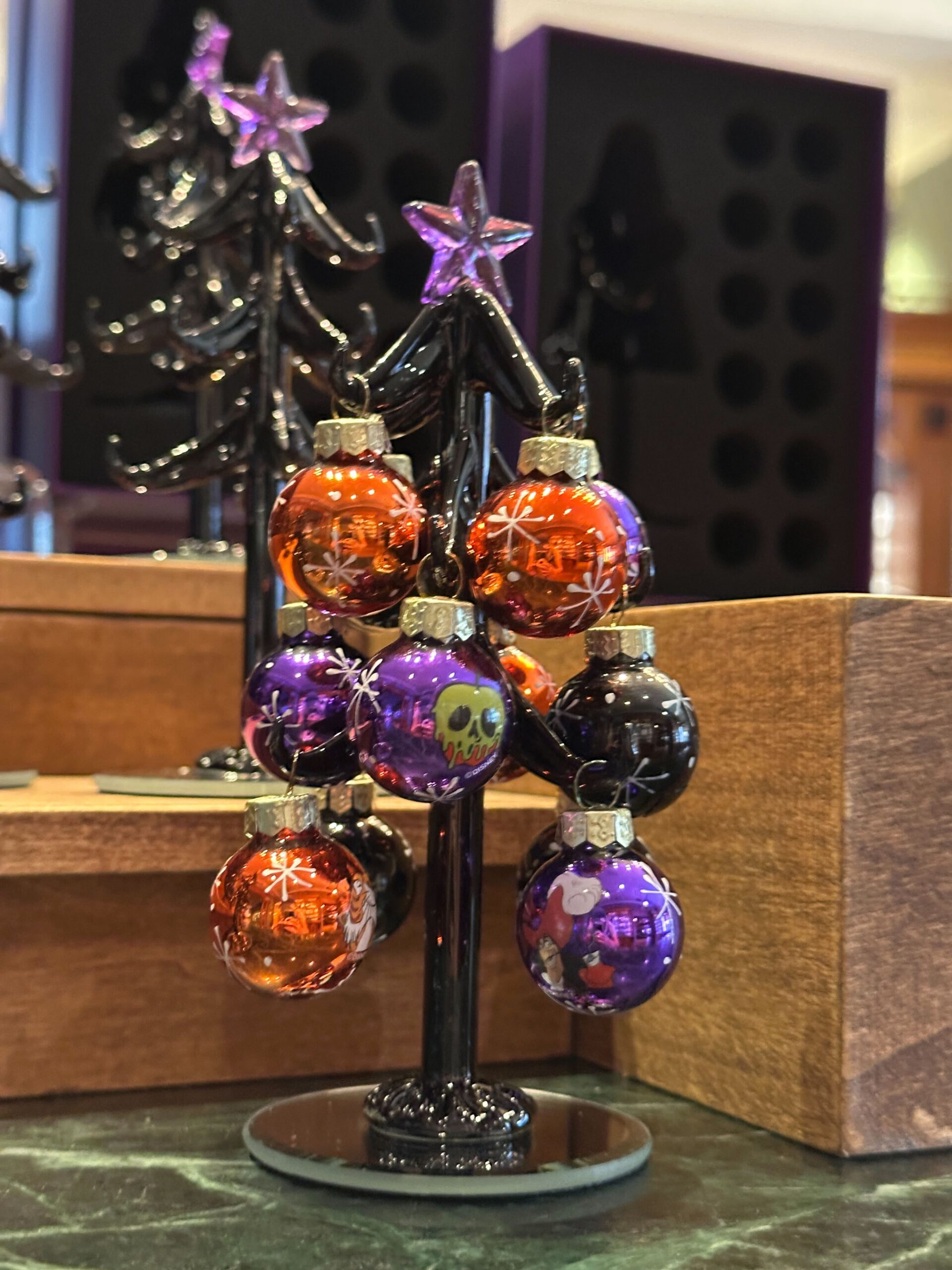 Small black tree holds Halloween Glass Trees and Villain Ornaments in festive colors with a spooky star on top.