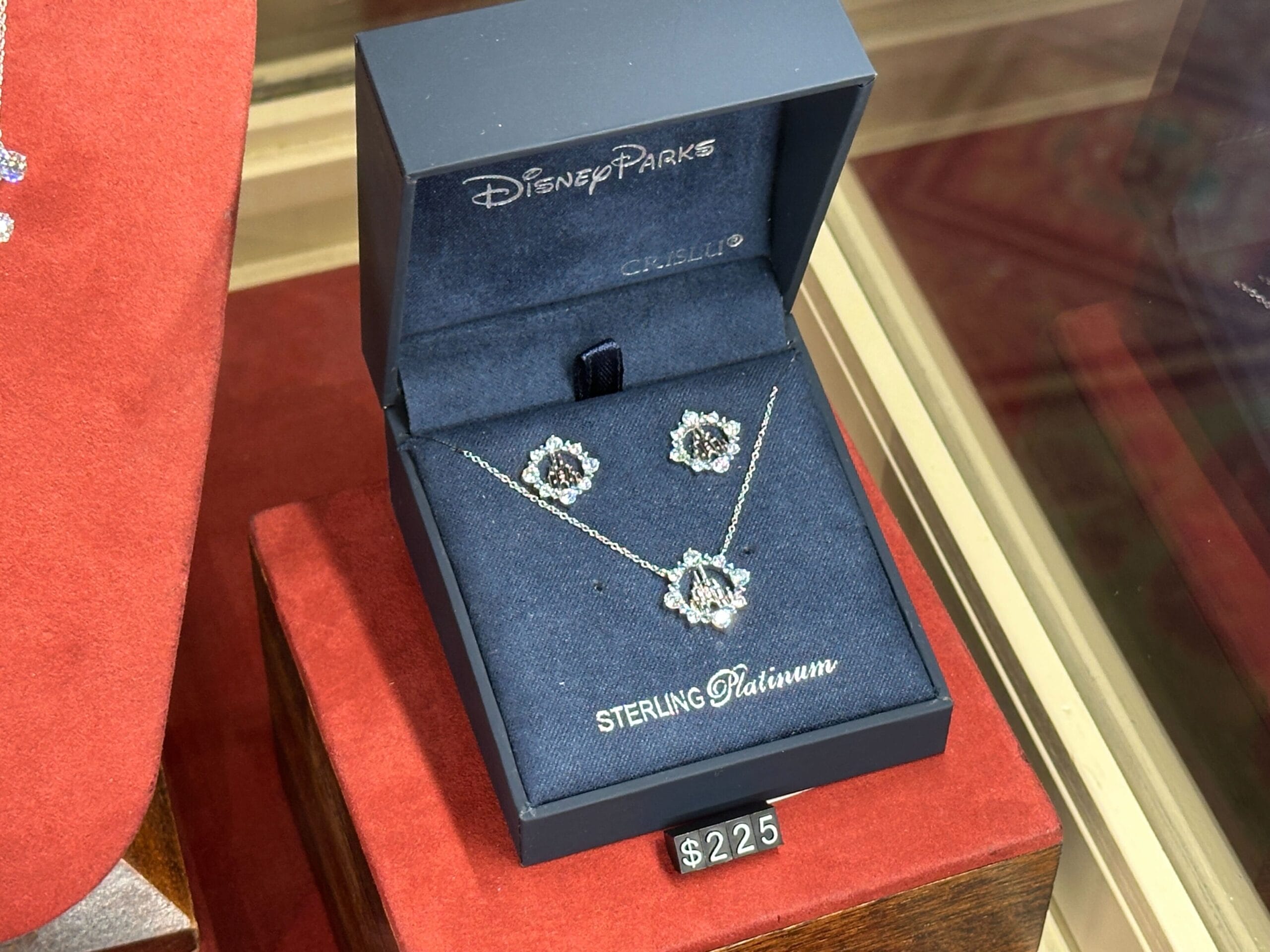 Disney Parks Fine Jewelry sterling platinum necklace & earrings set in a blue box, $225, displayed in a case.