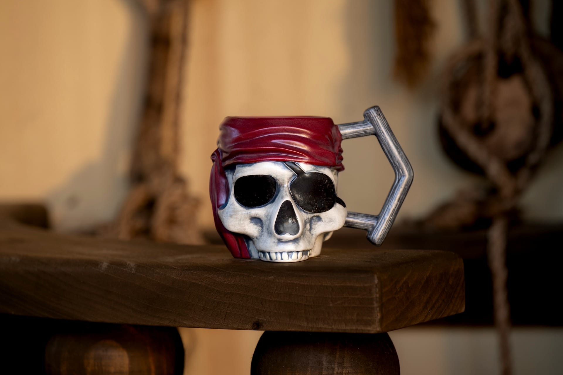 A mug shaped like a skull wearing a red bandana—perfect Pirates Merchandise from Cask & Cannon Bar—sits on wood.