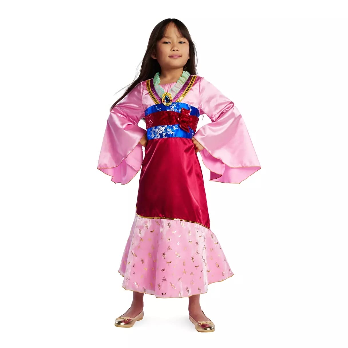 Young girl in a pink and red Disney Store princess dress, standing with hands on hips and smiling confidently for Halloween.