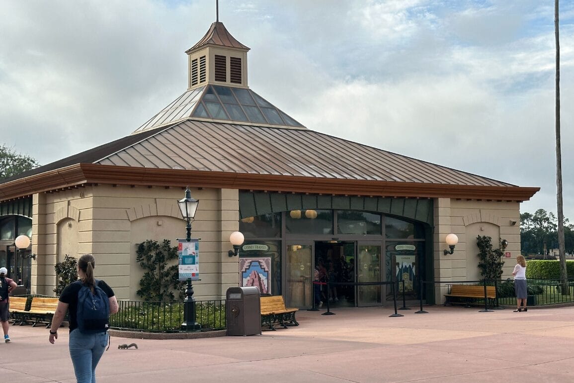 Hexagonal building with a brown metal roof, benches outside, and a Haunted Mansion vibe under a cloudy sky.