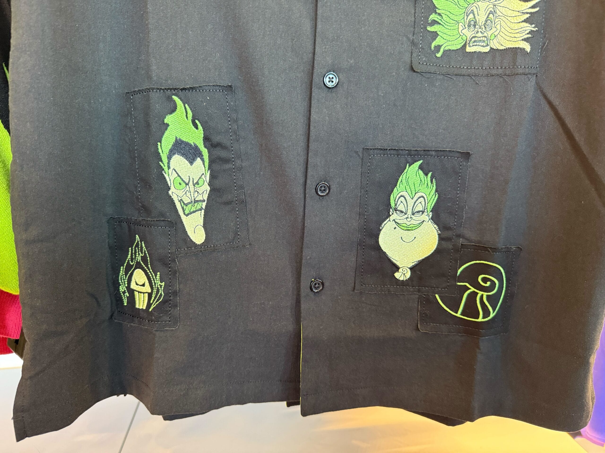 Black shirt with green embroidered Disney villains’ faces—perfect Disneyland or Halloween merchandise for fans.