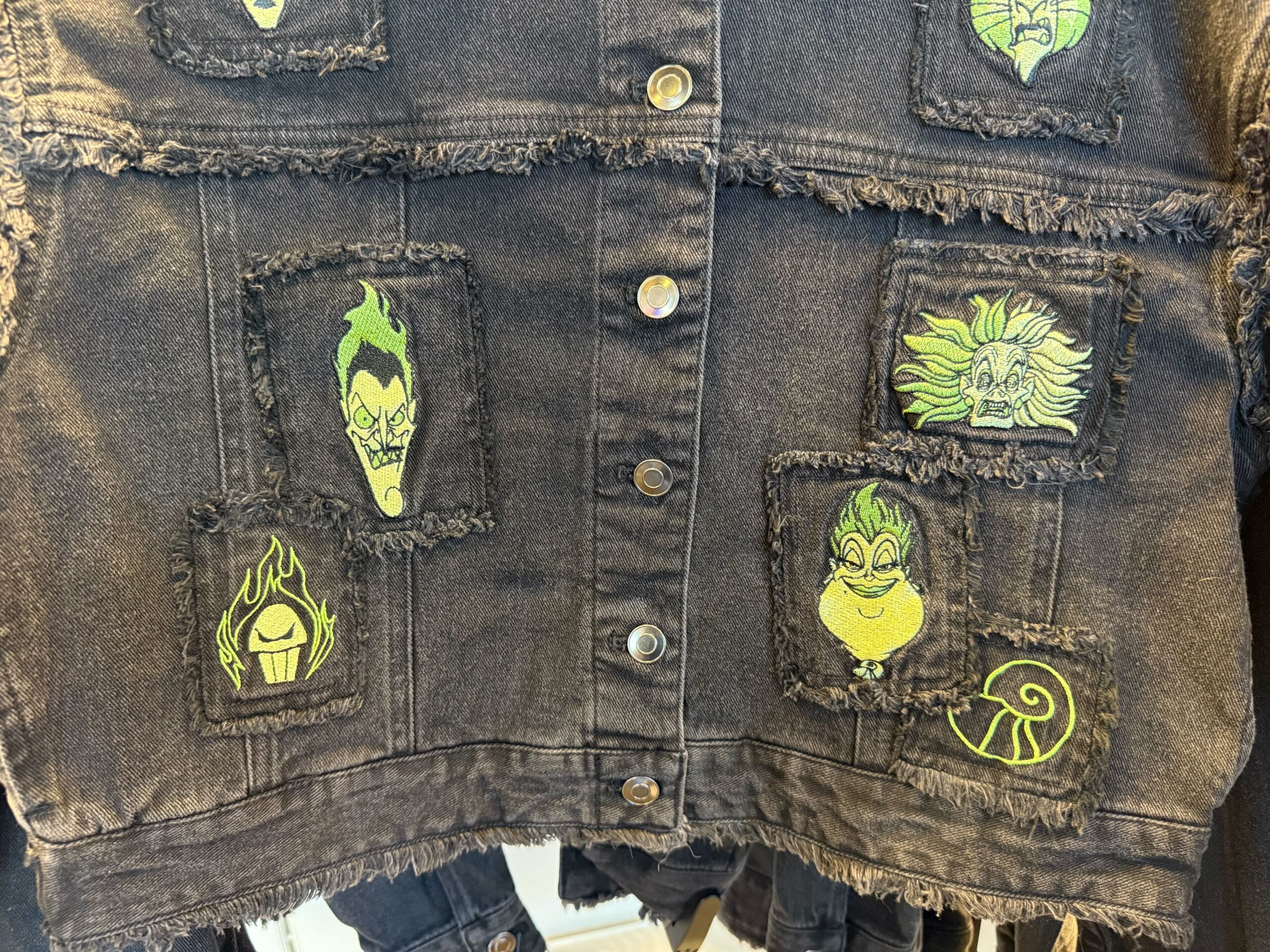 Black denim jacket with green and yellow cartoon villain patches—perfect for fans of Disneyland villains merchandise.