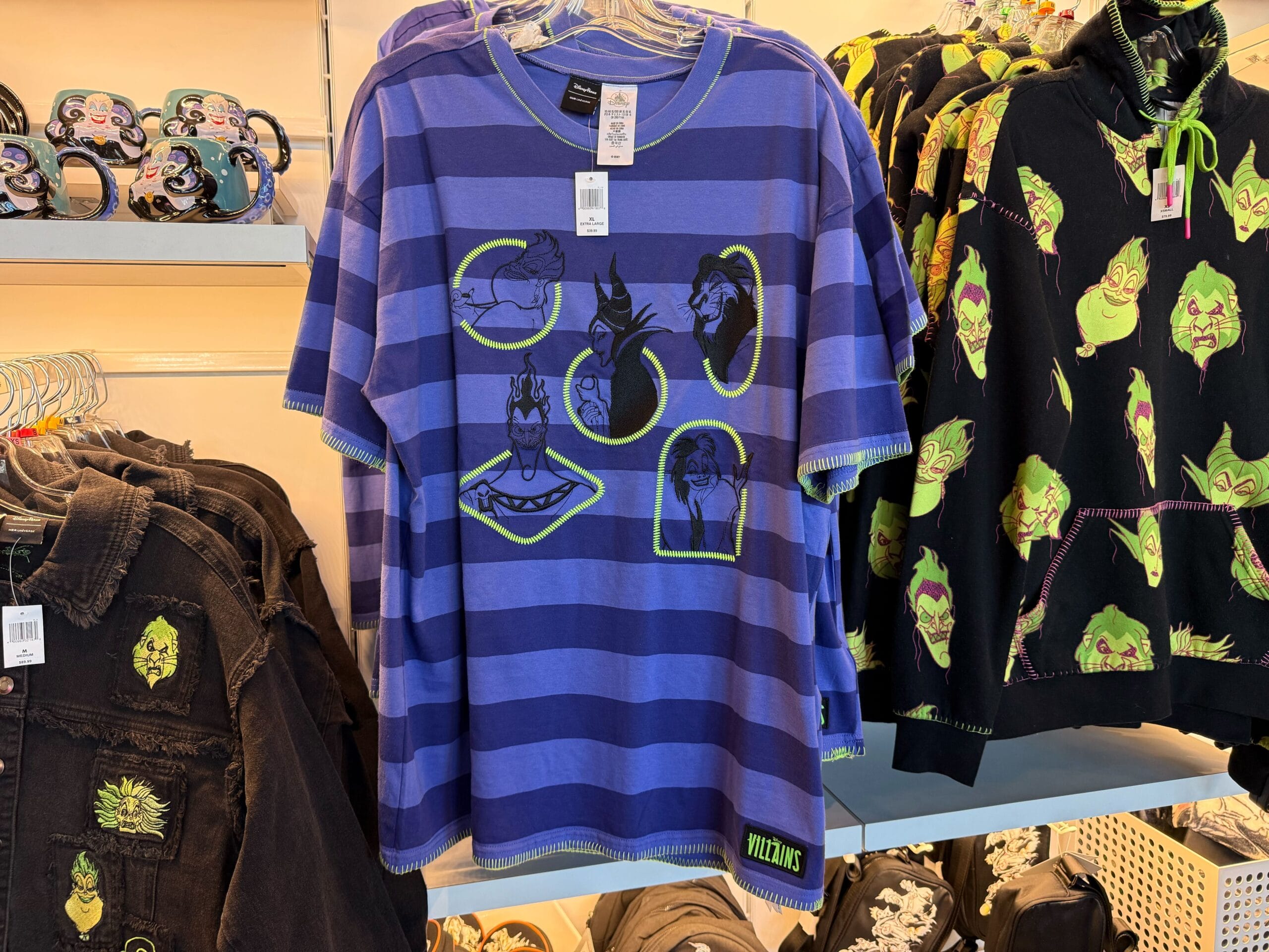 Blue and purple striped shirt with Disney villains' faces, part of Disneyland Villains merchandise on a themed clothing rack.