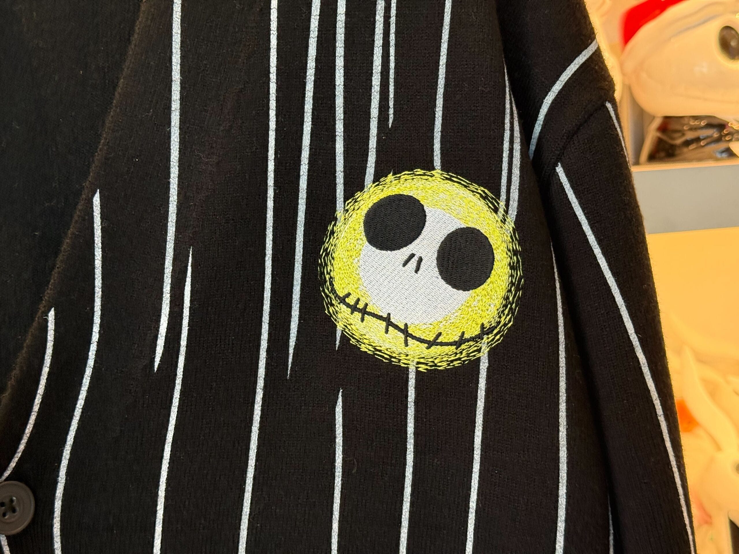 Black jacket with white pinstripes and a yellow, stitched Jack Skellington face patch—perfect Halloween merchandise.