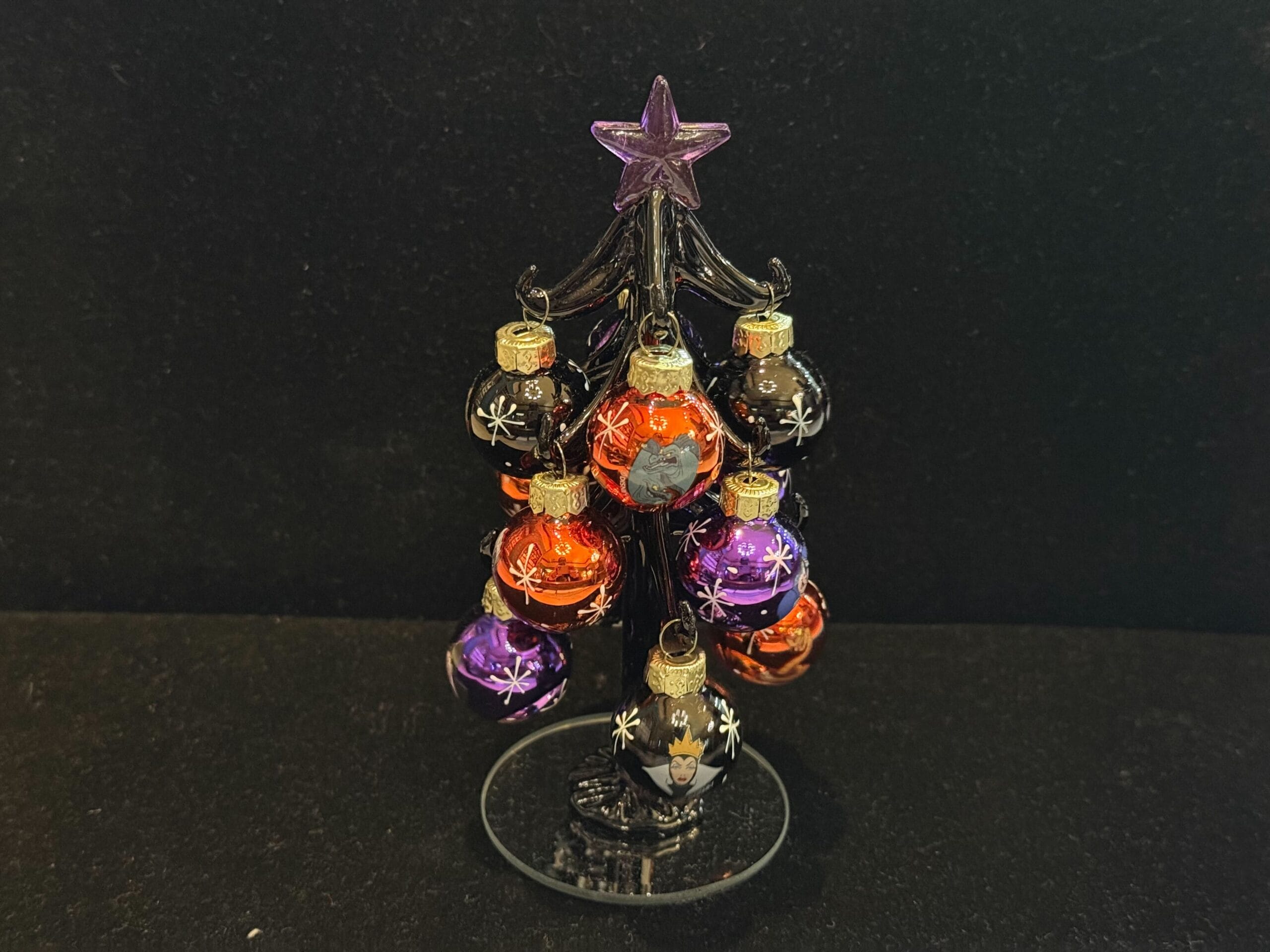 Miniature black Christmas tree with purple star, decorated with black, orange, and purple ornaments featuring villain faces.