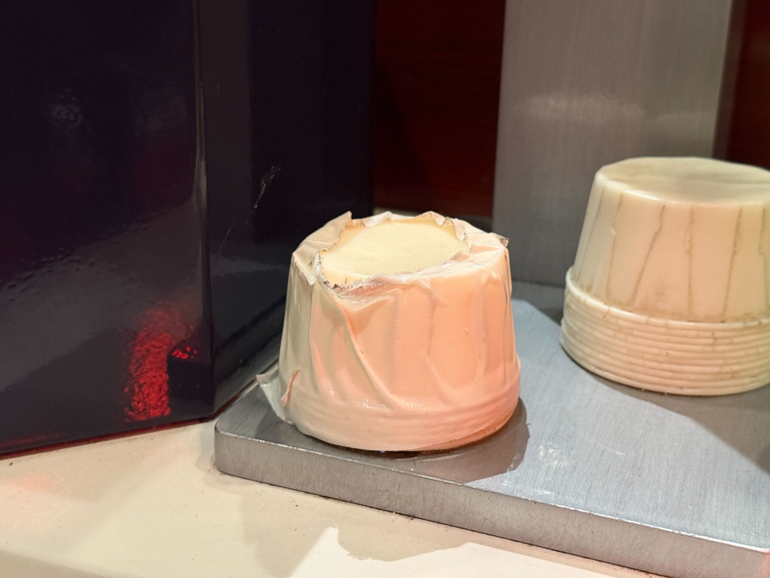 A stack of disposable white paper cups, perfect for cell phone use in an outdoor queue, sits on a metal surface.