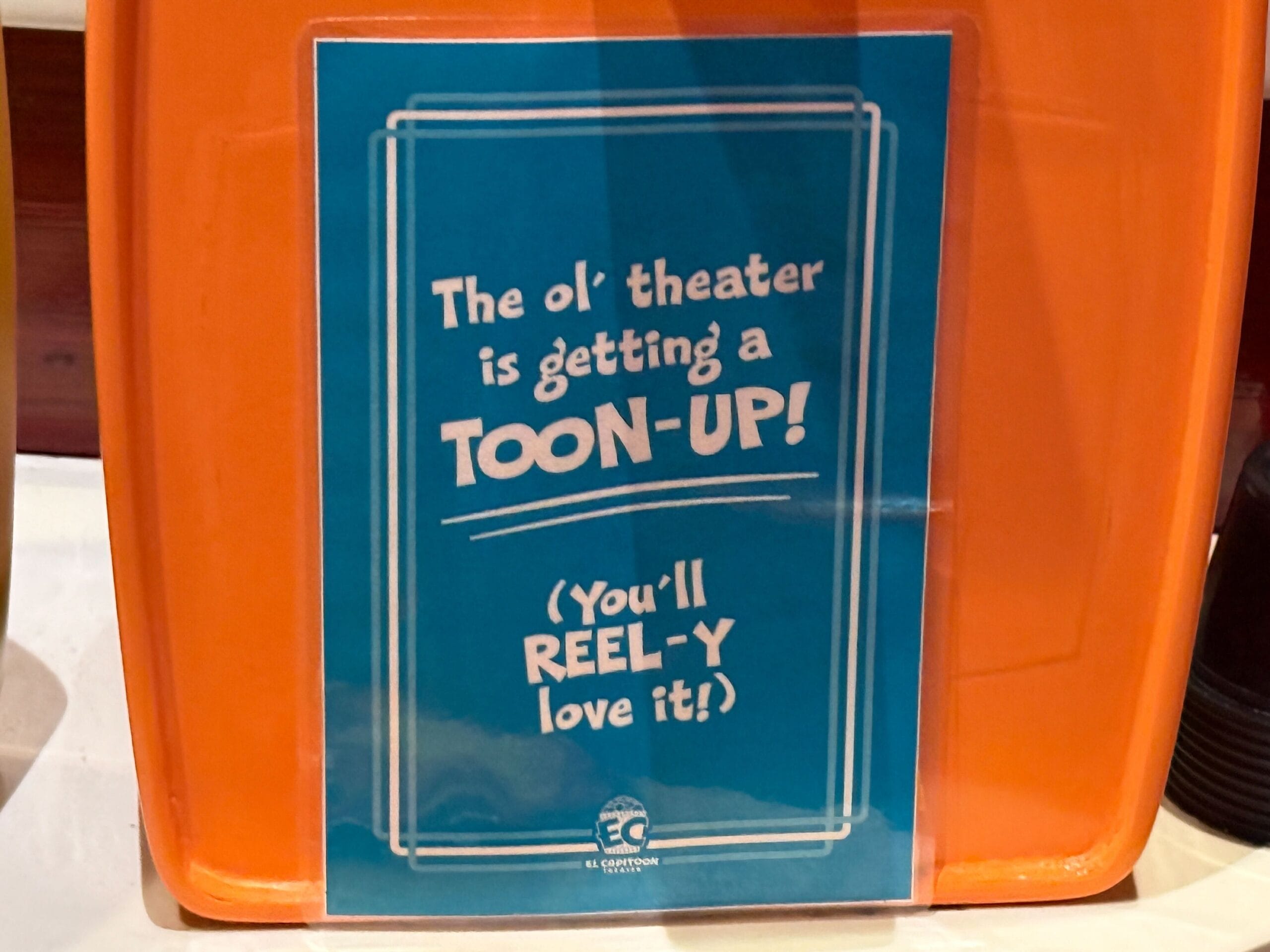 Blue sign on an orange stand in the outdoor queue for Mickey & Minnie's Runaway Railway reads: "The ol' theater is getting a TOON-UP!