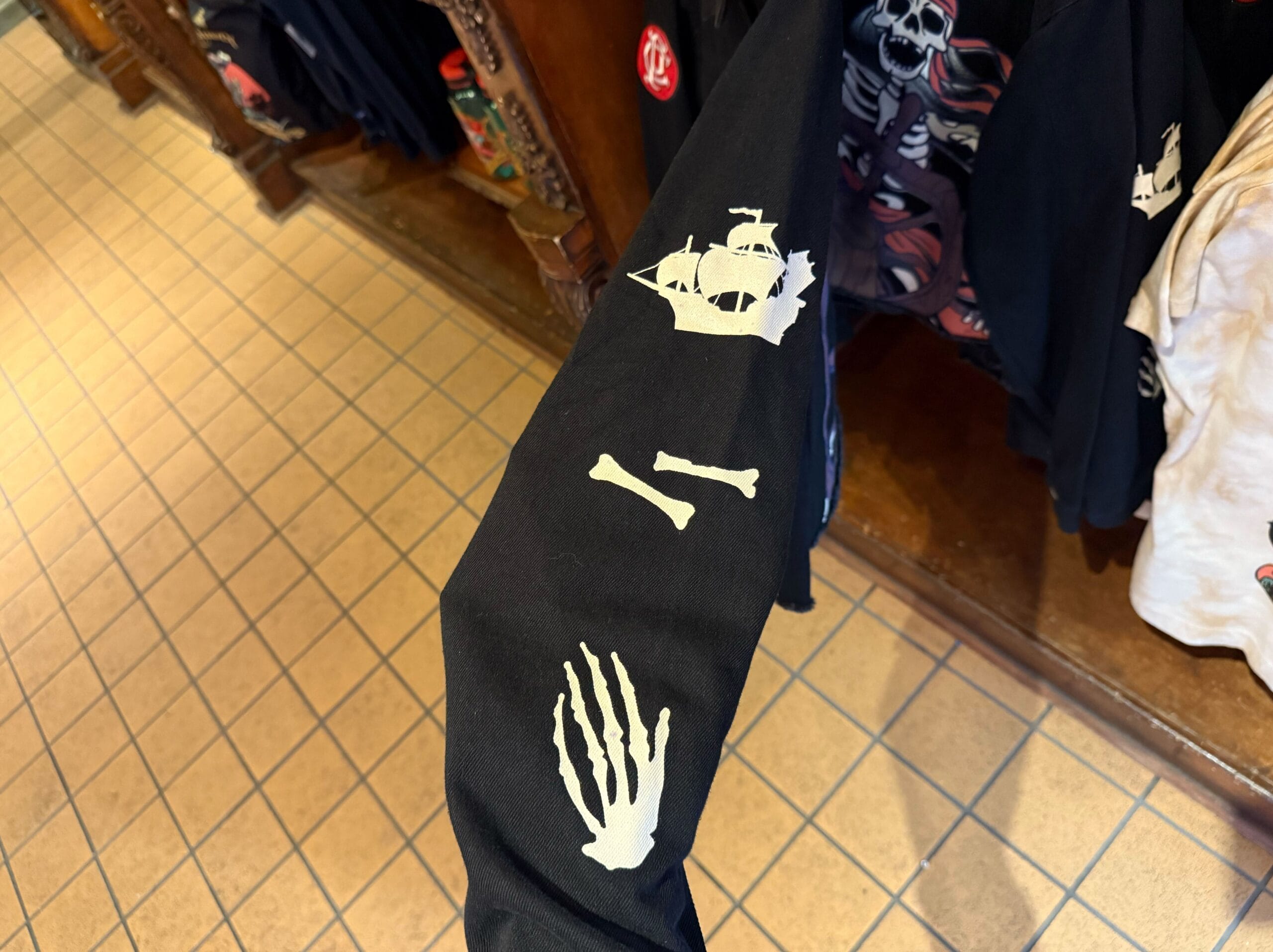 Black sleeve with white Pirates of the Caribbean prints, featured as new merchandise in a Disneyland apparel store.