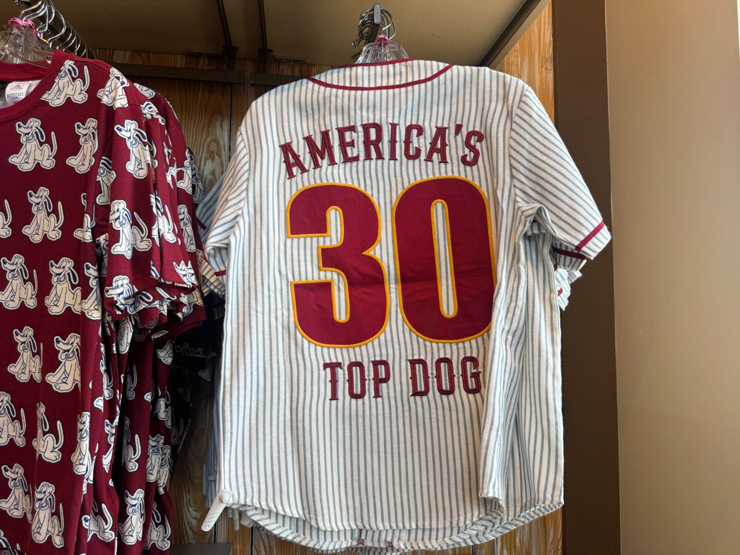A striped jersey with "AMERICA'S 30 TOP DOG" in red and yellow letters hanging on a rack.
