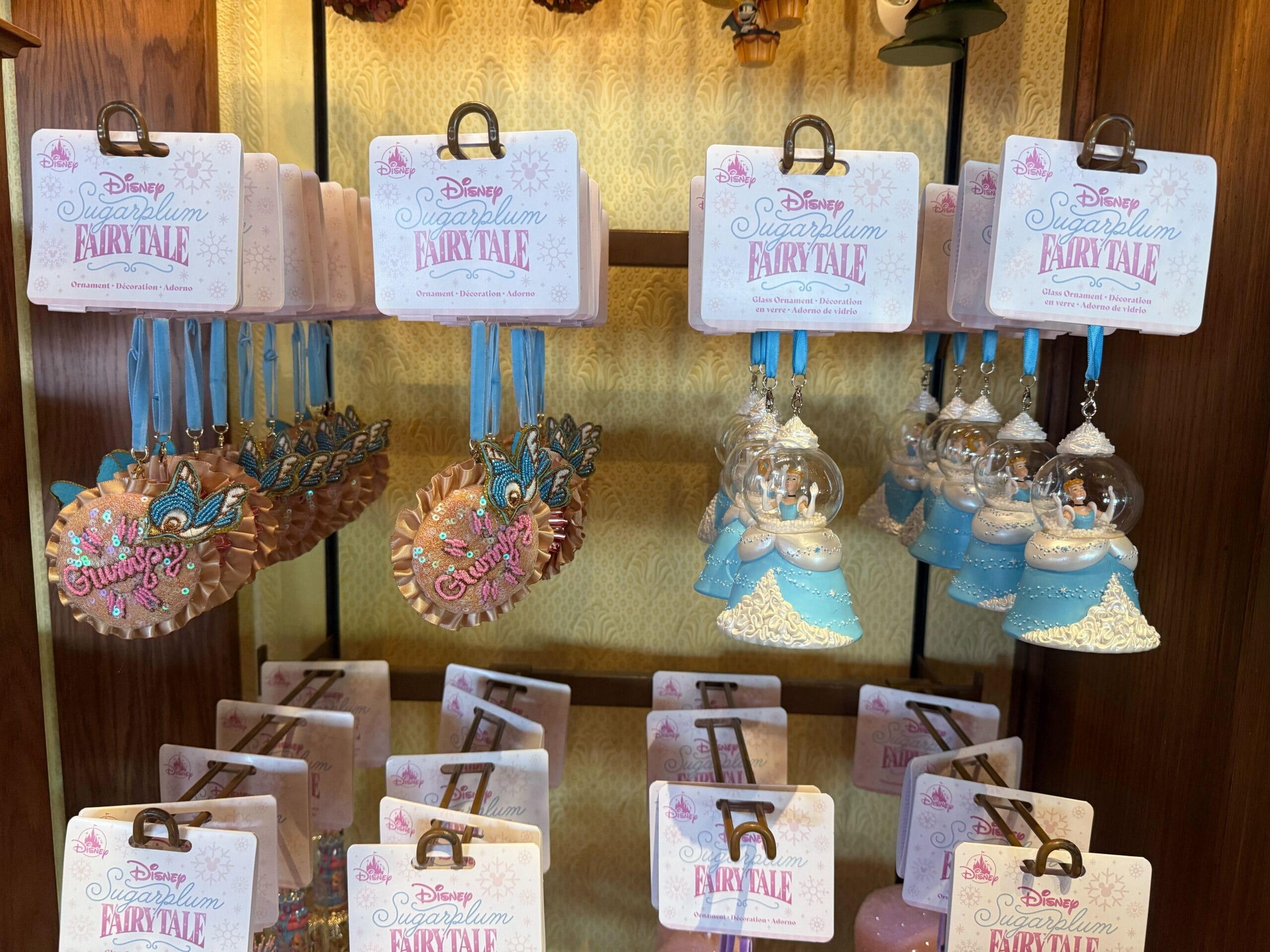 Disney Princess Cinderella ornaments, tiaras, and snow globes displayed on a store shelf with fairy tale tags.