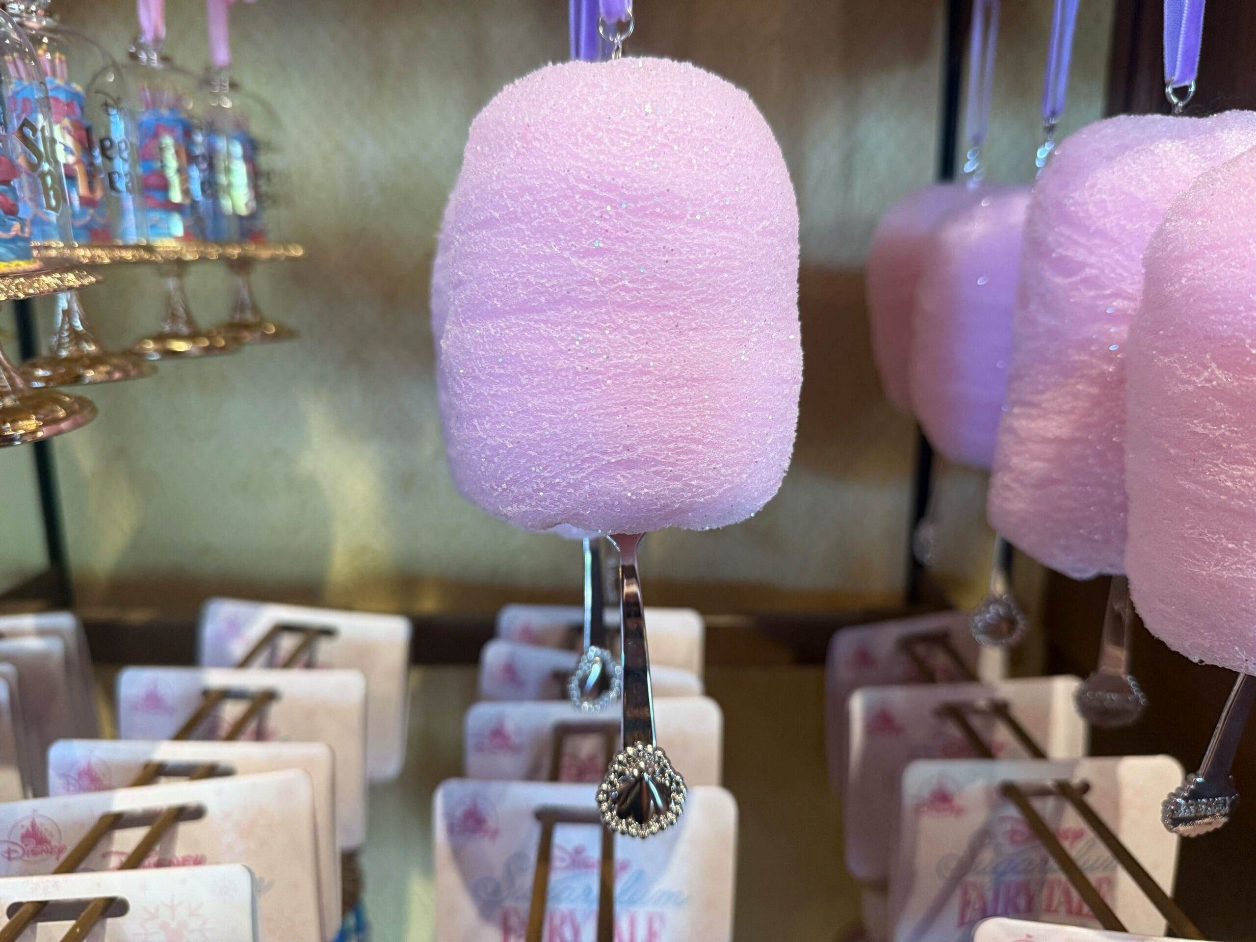 A pink Sugarplum Princess Ornament with a silver stick and jewel detail, hanging on display in the Ornament Collection.