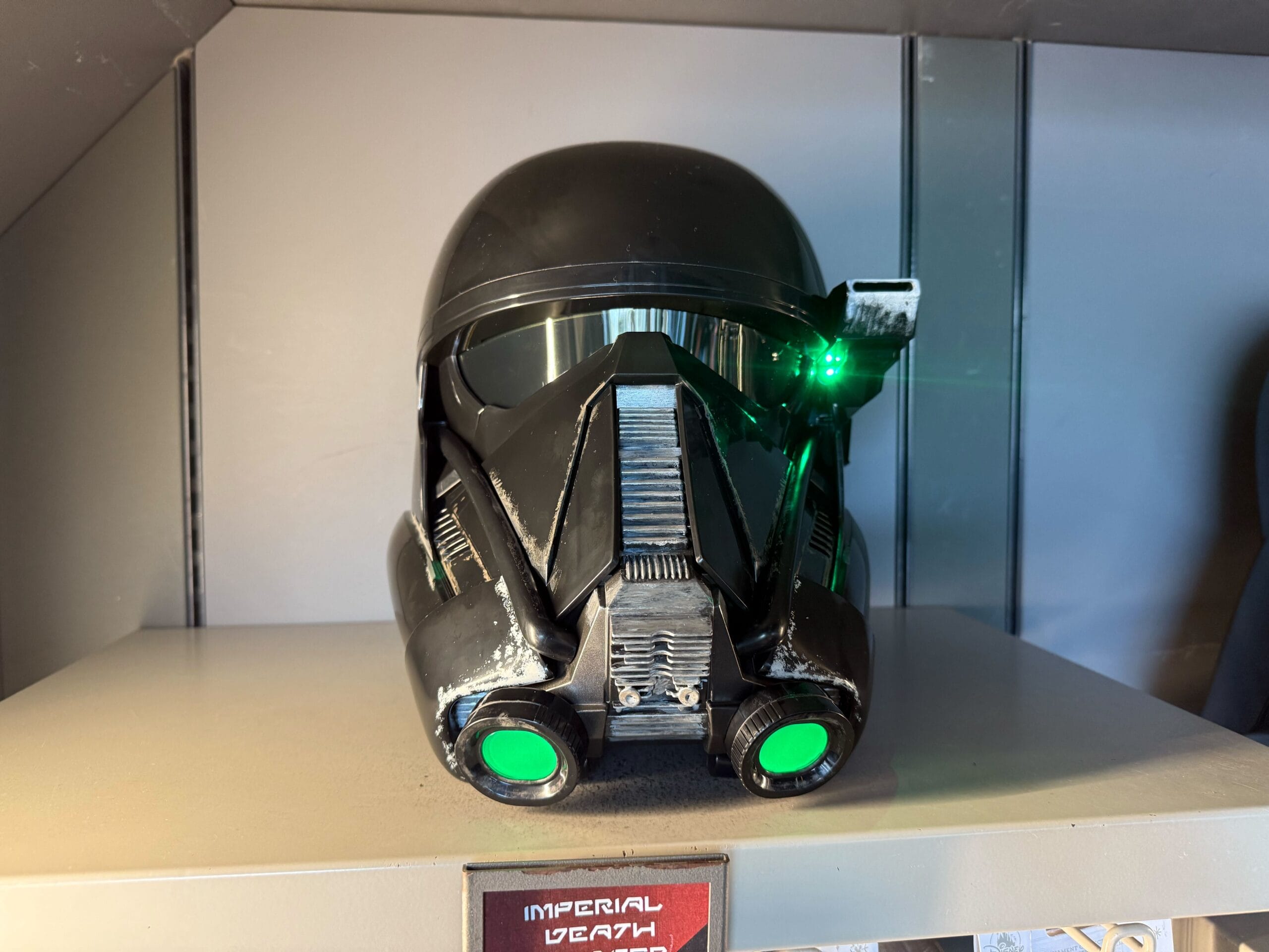 A black Star Wars Death Trooper helmet with glowing green lights, just like those seen at Galaxy's Edge, on display.