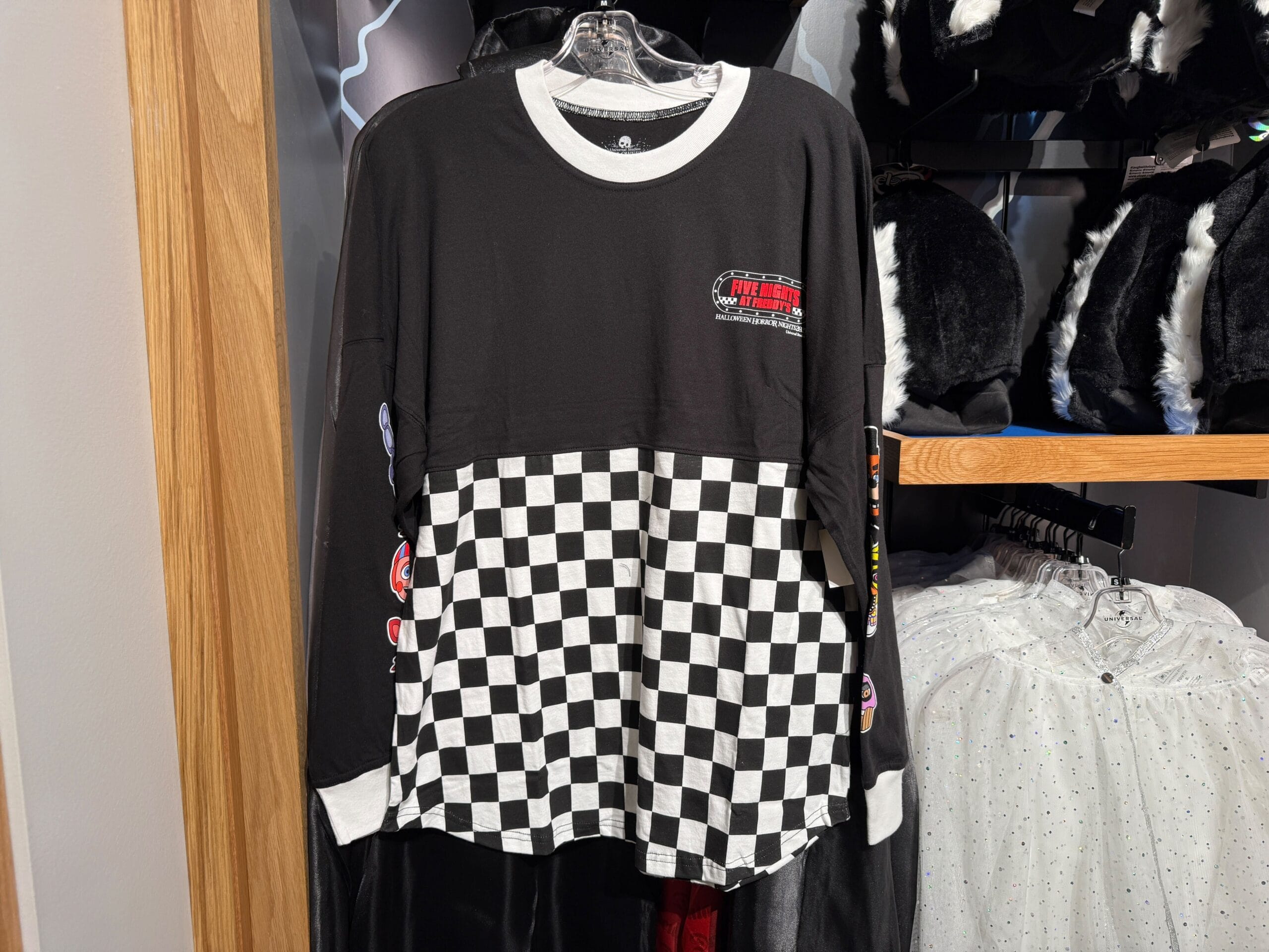 Black and white checkerboard racing shirt, perfect for Five Nights at Freddy's fans, hangs on a display rack.