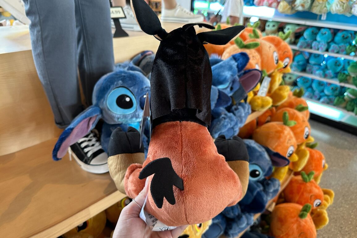 A person holds a plush toy resembling Goofy’s face in a store with other plush toys in the background.