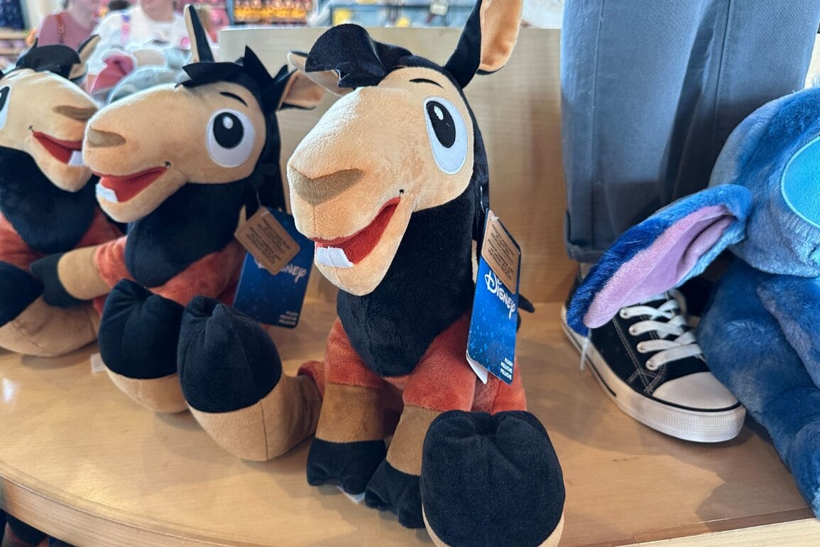 A plush toy of Kuzco as a llama from Disney's "The Emperor's New Groove" displayed on a store shelf.