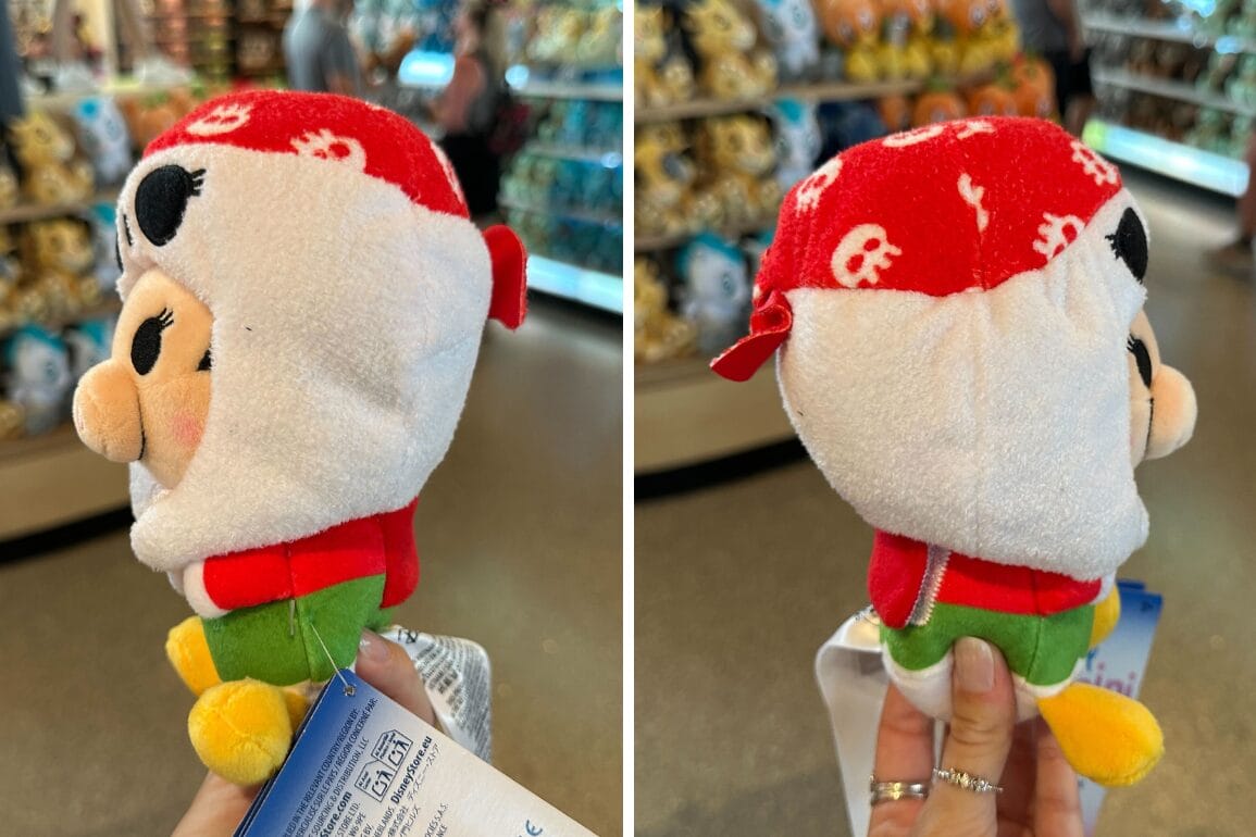 Plush toy with red skull-patterned hood and green shirt, like Pirate Mini Mix-Its, shown in a Walt Disney World store.