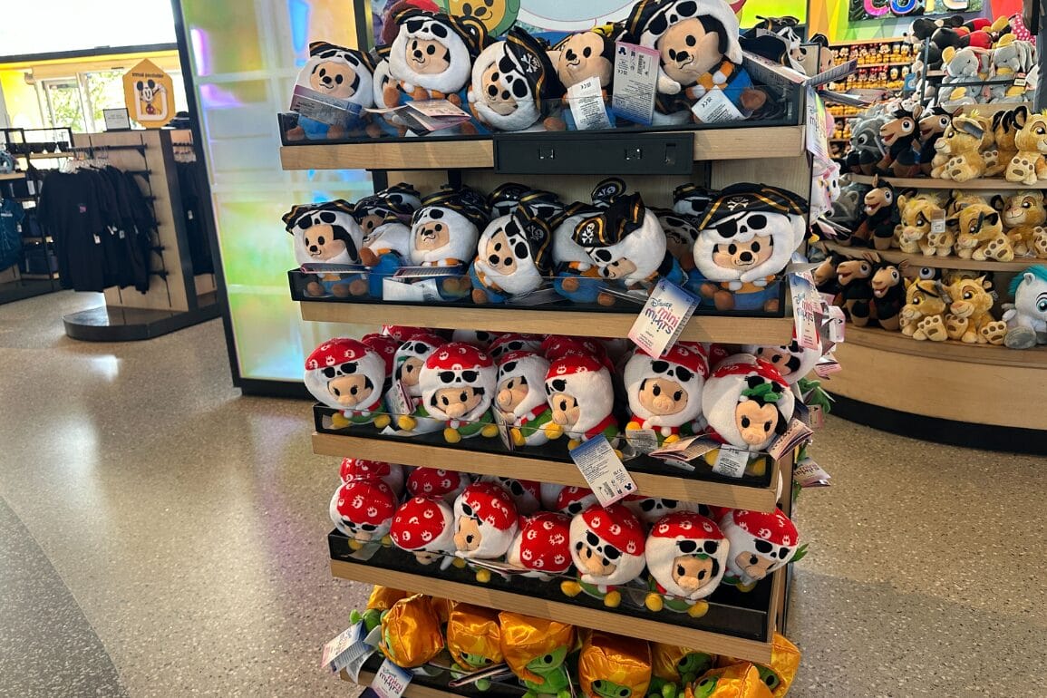 A store display of Walt Disney World plush toys featuring Goofy and Clarabelle dressed as pirates on wooden shelves.