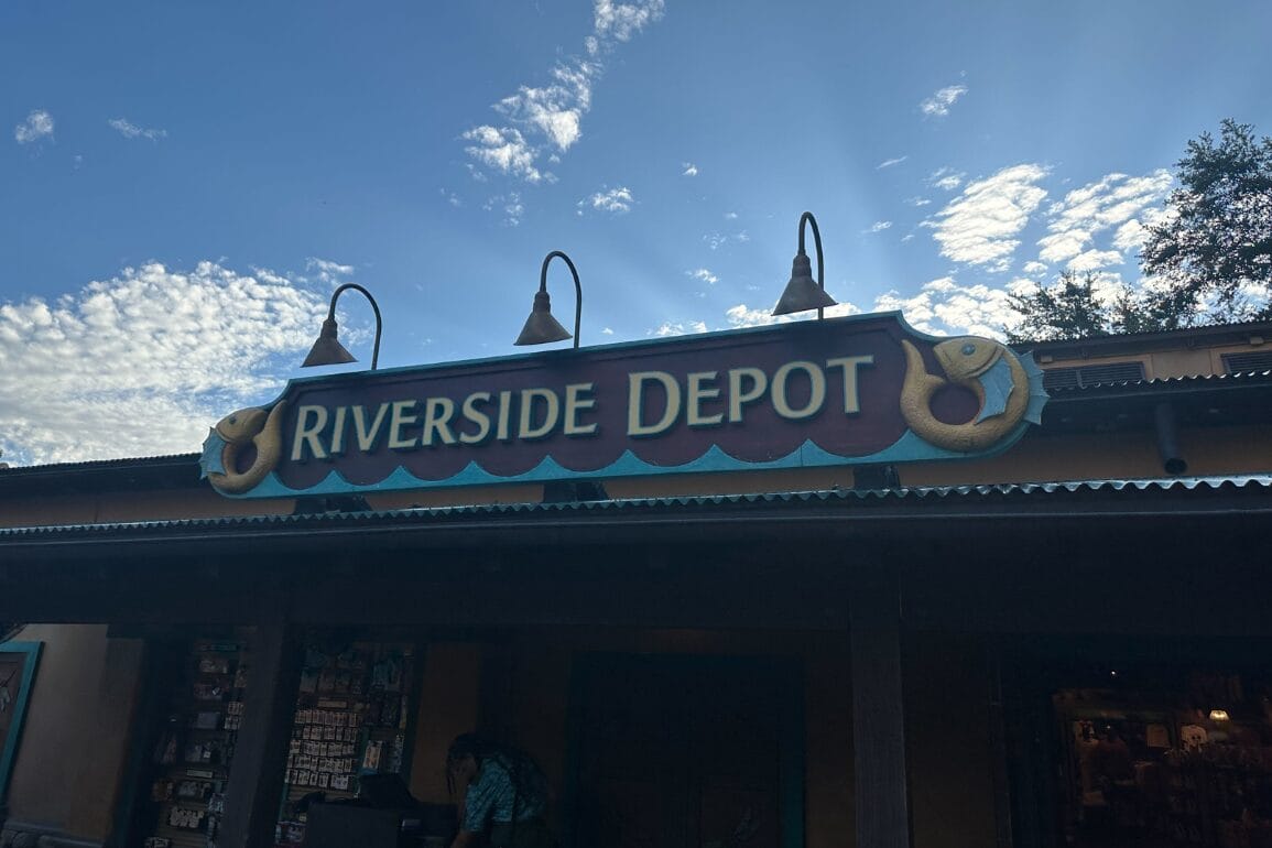 Riverside Depot store sign with fish decor under blue skies at Walt Disney World.