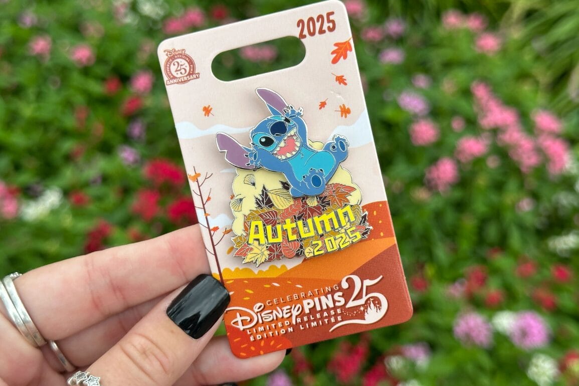 A hand holds a limited-edition Stitch pin on autumn leaves, labeled "Autumn 2025," perfect for Disney or Haunted Mansion Pins fans.