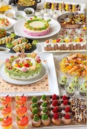 A colorful buffet table at Tokyo Disneyland with cakes, cupcakes, shrimp, sushi, fruit desserts, and appetizers arranged neatly.