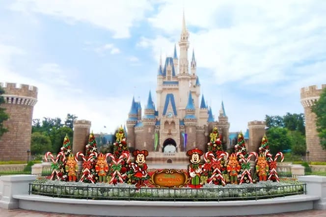 Disney castle at Tokyo Disneyland with Christmas decorations, candy canes, Mickey & Minnie, and festive parade trees in front.