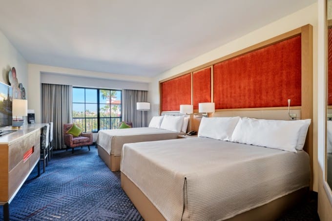 Updated guest room at Hard Rock Hotel with two large beds, a TV, and a view of palm trees at Universal Orlando Resort.