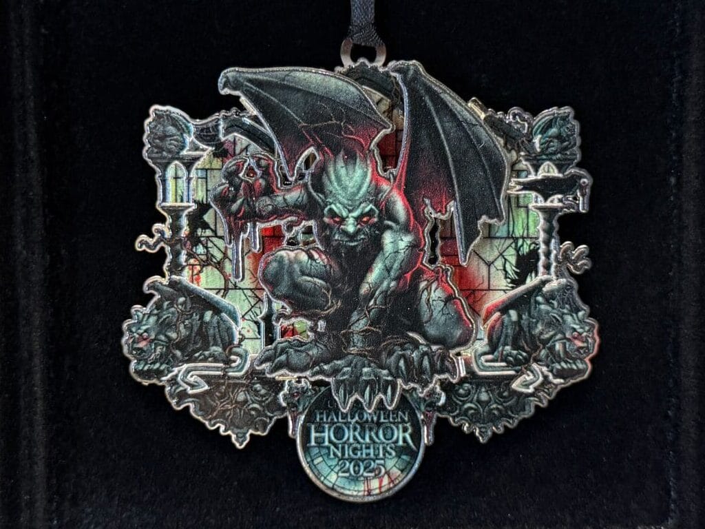 A hand holds a black box with a detailed Maleficent dragon, displayed among Universal Orlando Resort HHN merch 2025.