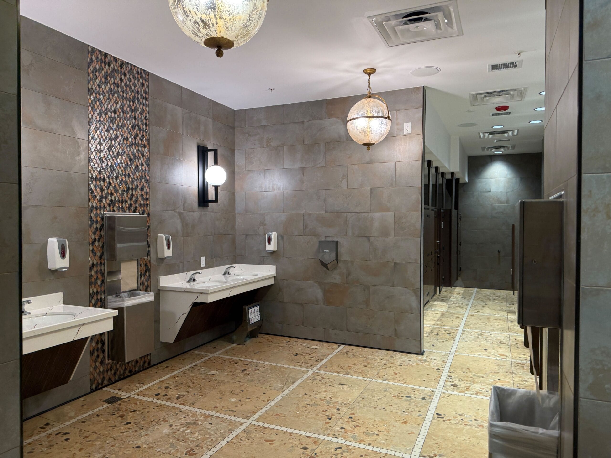 Modern Port of Entry Restrooms with tiled walls, sinks, and stalls at Universal Islands of Adventure after refurbishment.