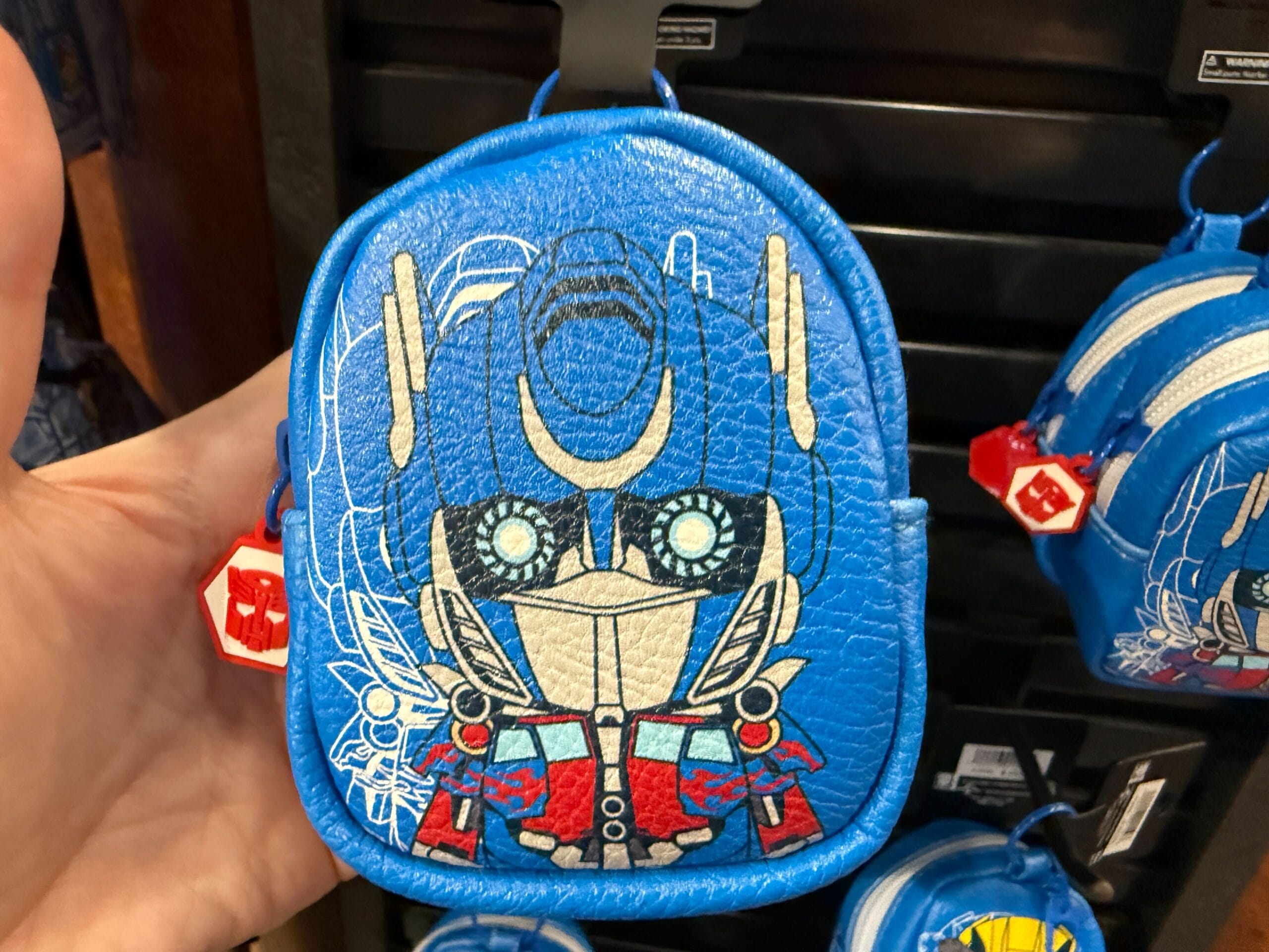 Blue coin purse with a cartoon robot face design, resembling Optimus Prime from Transformers, held in someone's hand.