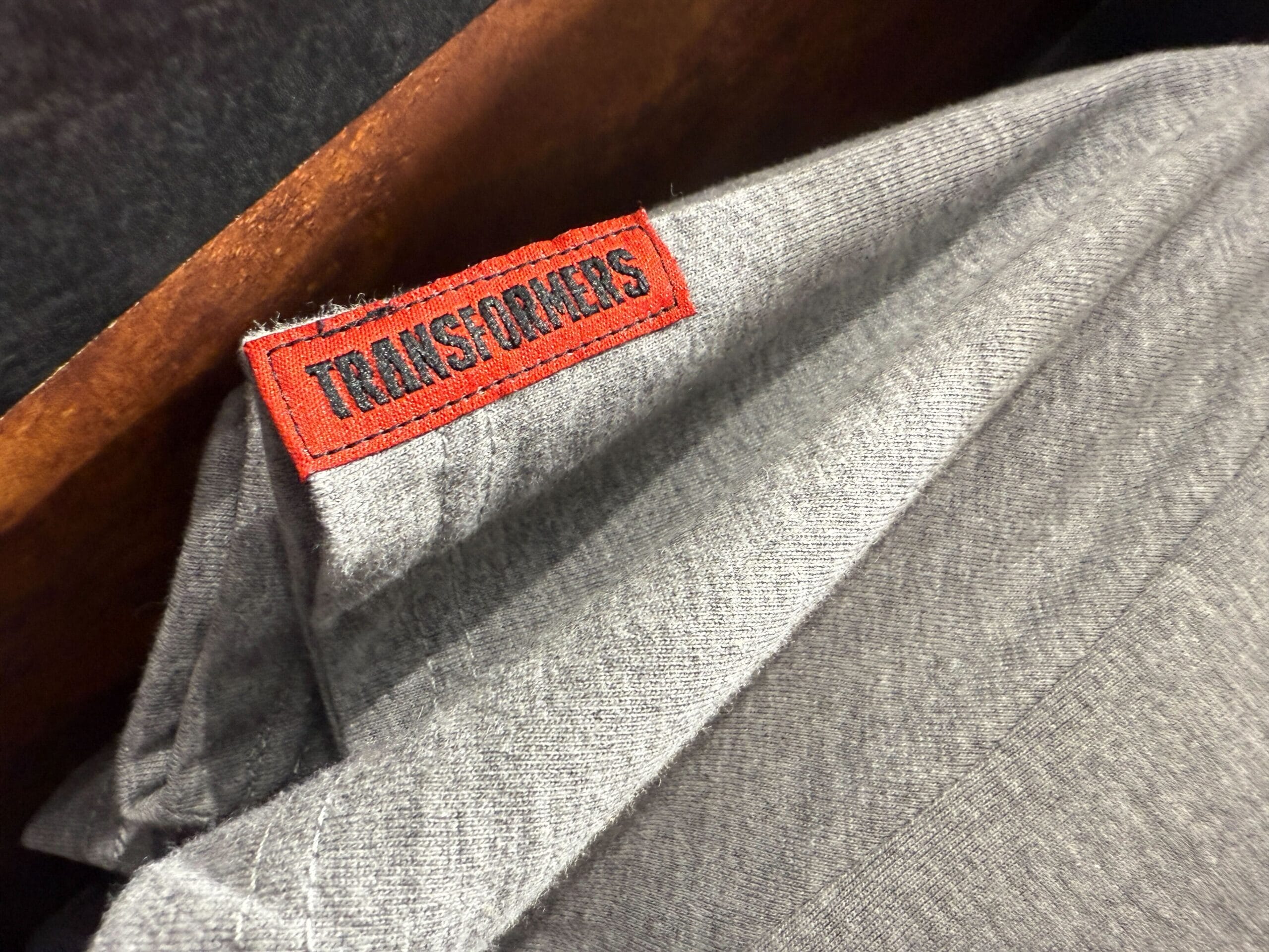 A gray fabric with a red tag that reads "TRANSFORMERS" in black text is shown up close.