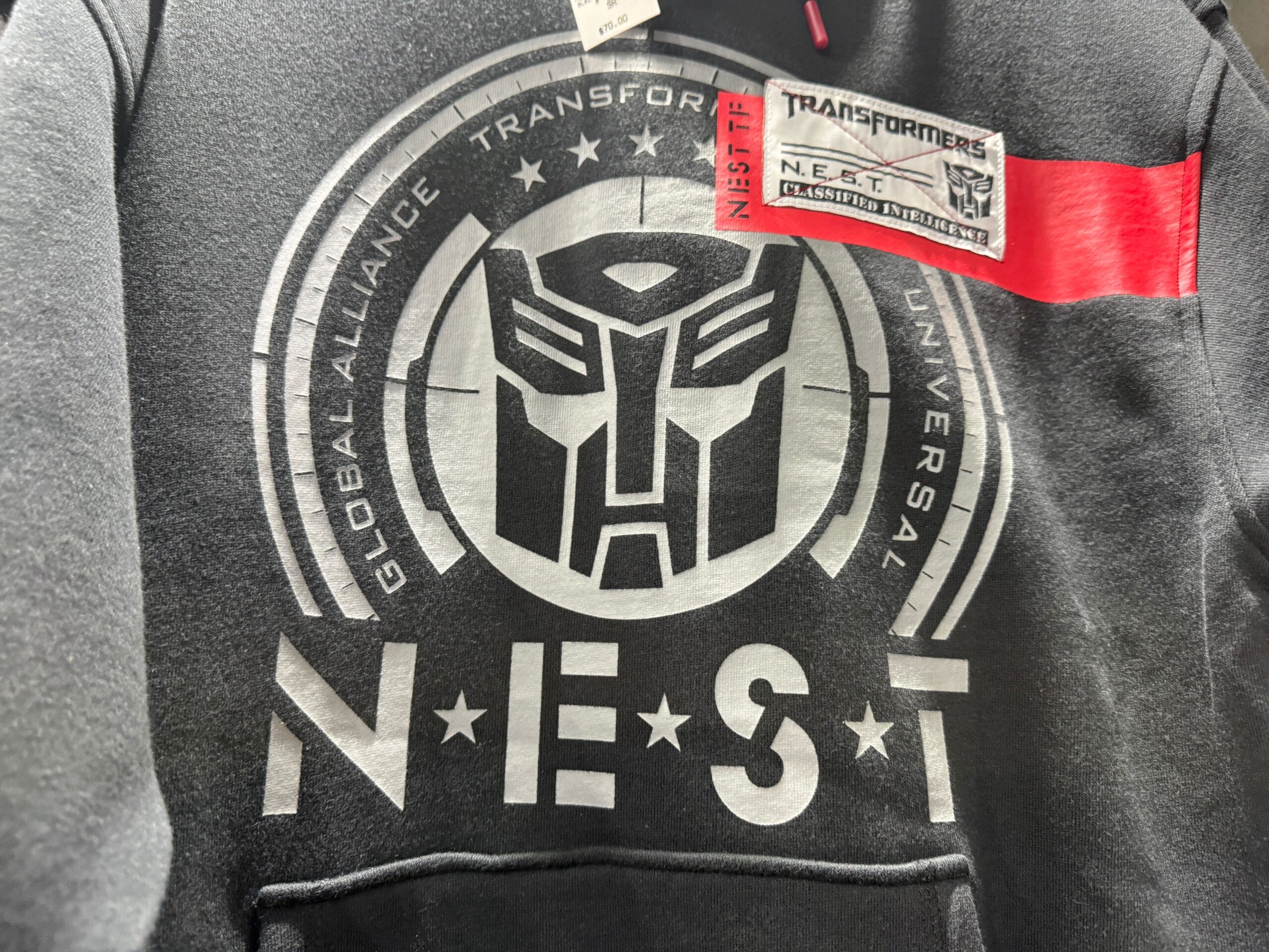Black hoodie with a large Transformers N.E.S.T. logo and a patch reading "Transformers N.E.S.T. Classified Intelligence.